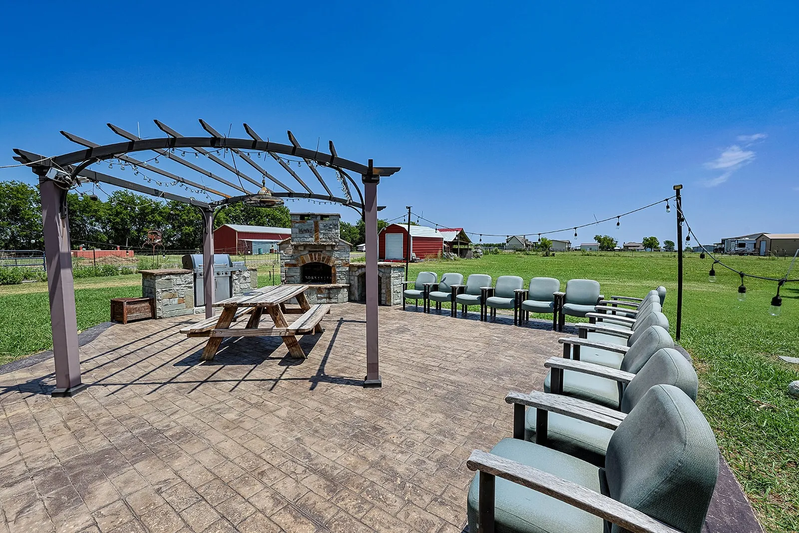 Expansive outdoor patio featuring an overhead pergola and stamped concrete flooring
