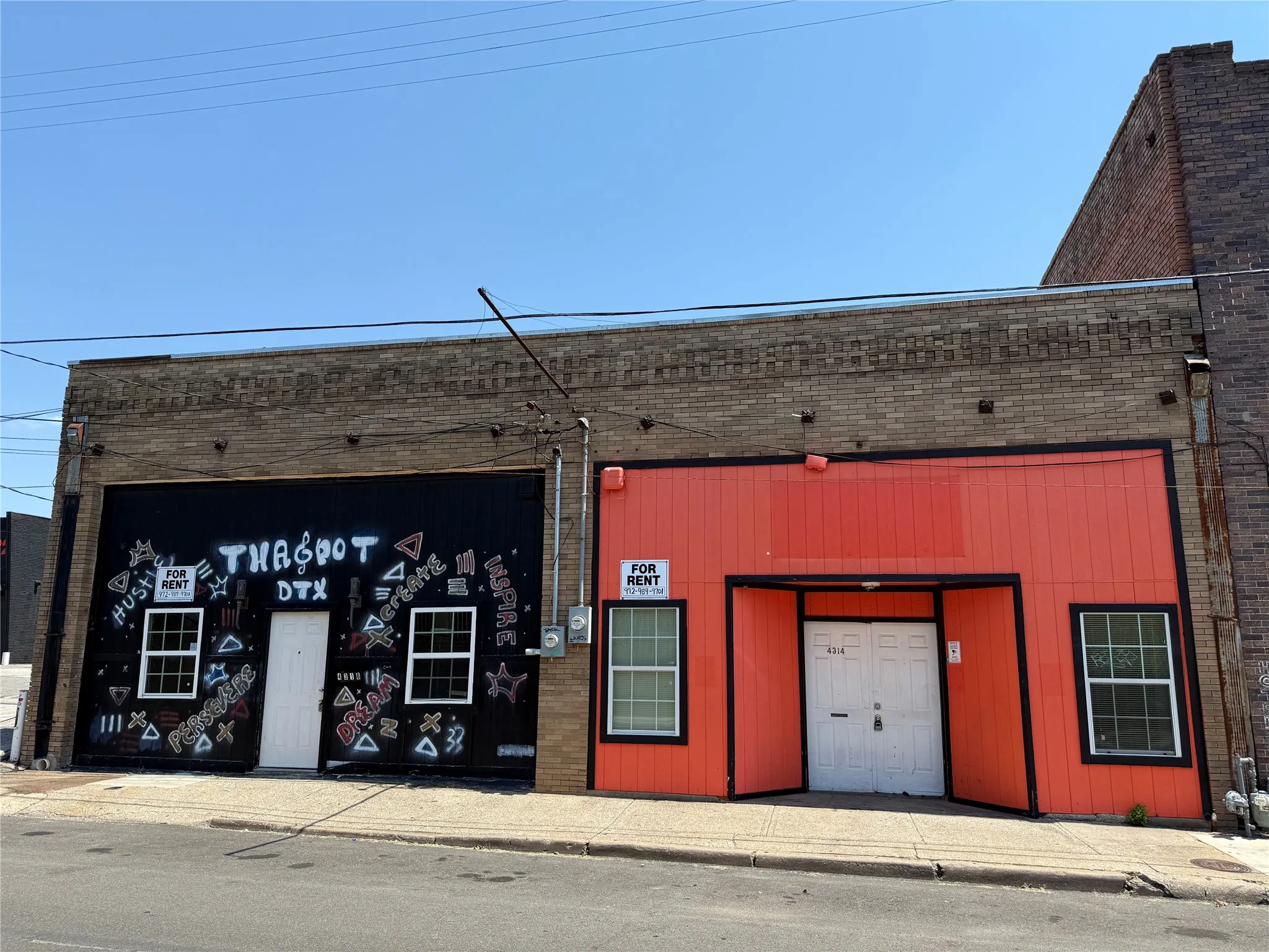 Commercial building featuring a brick facade with a black storefront section and an orange storefront section