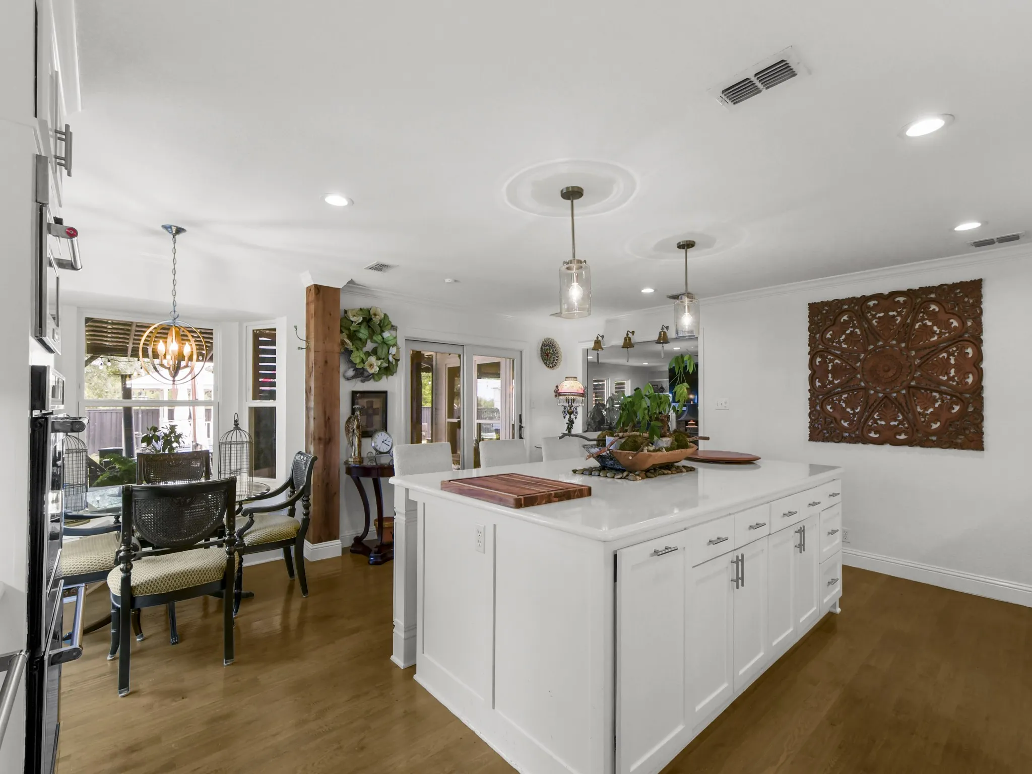 Kitchen island with white cabinetry, a light-colored countertop, and two pendant lights