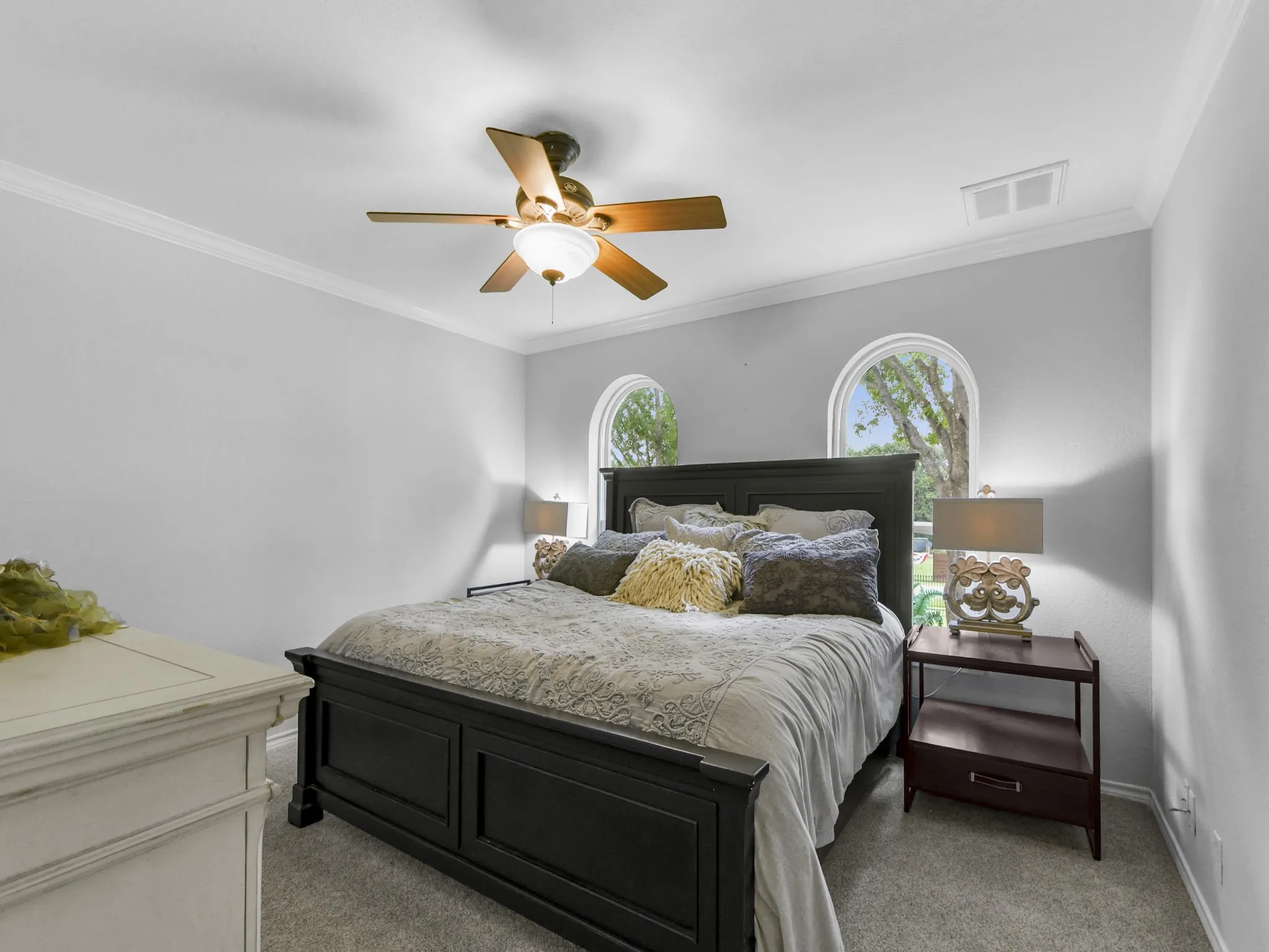 Bedroom featuring two arched windows, light gray walls, and crown molding
