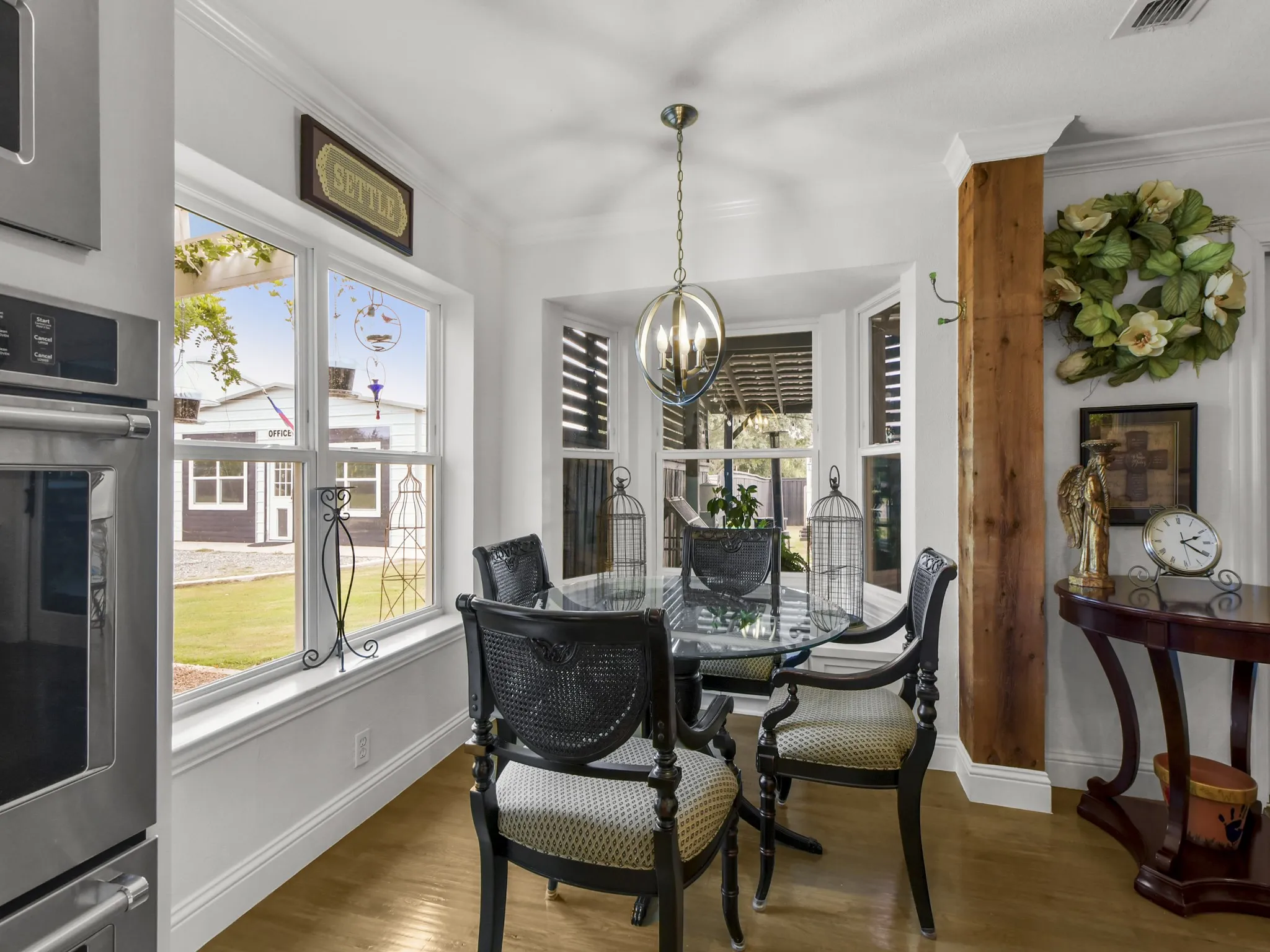 Dining area with a bay window, wood-finish flooring, a built-in oven, and a wood beam architectural detail
