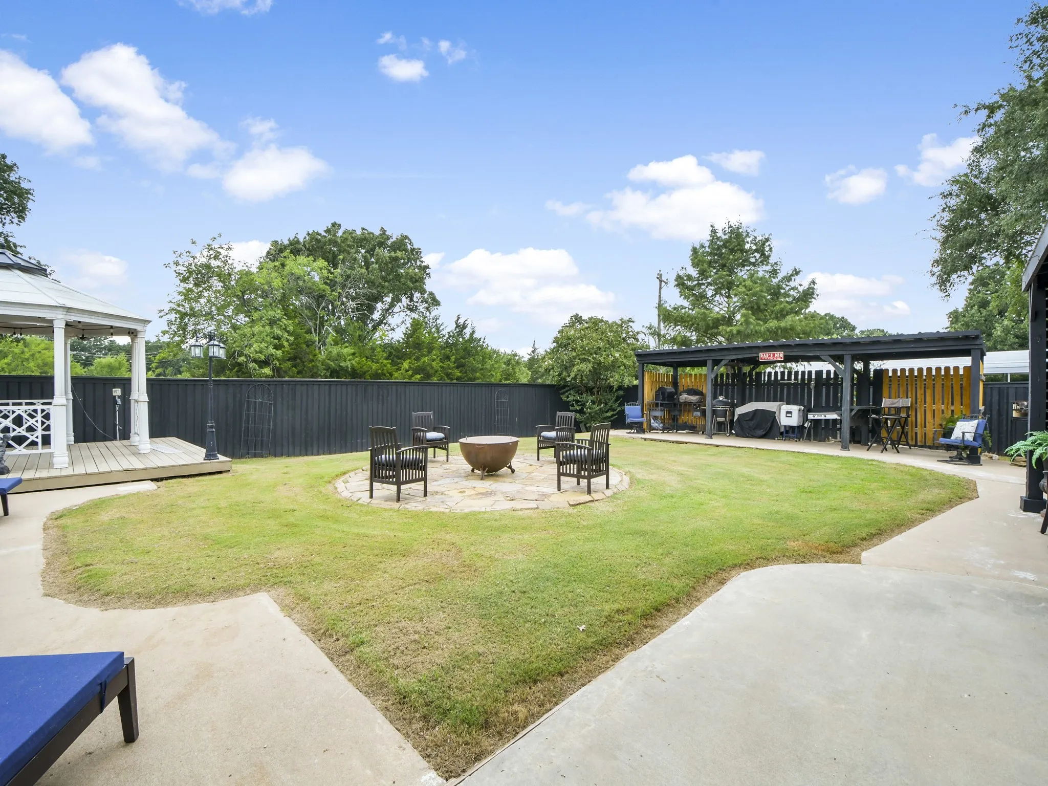 Expansive backyard featuring a large lawn, a paved patio, and a white gazebo with a wooden deck