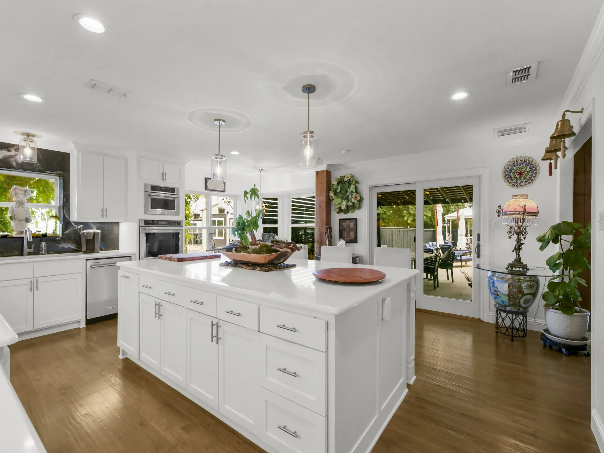 White kitchen featuring a large central island with storage, stainless steel appliances, and wood-finish flooring