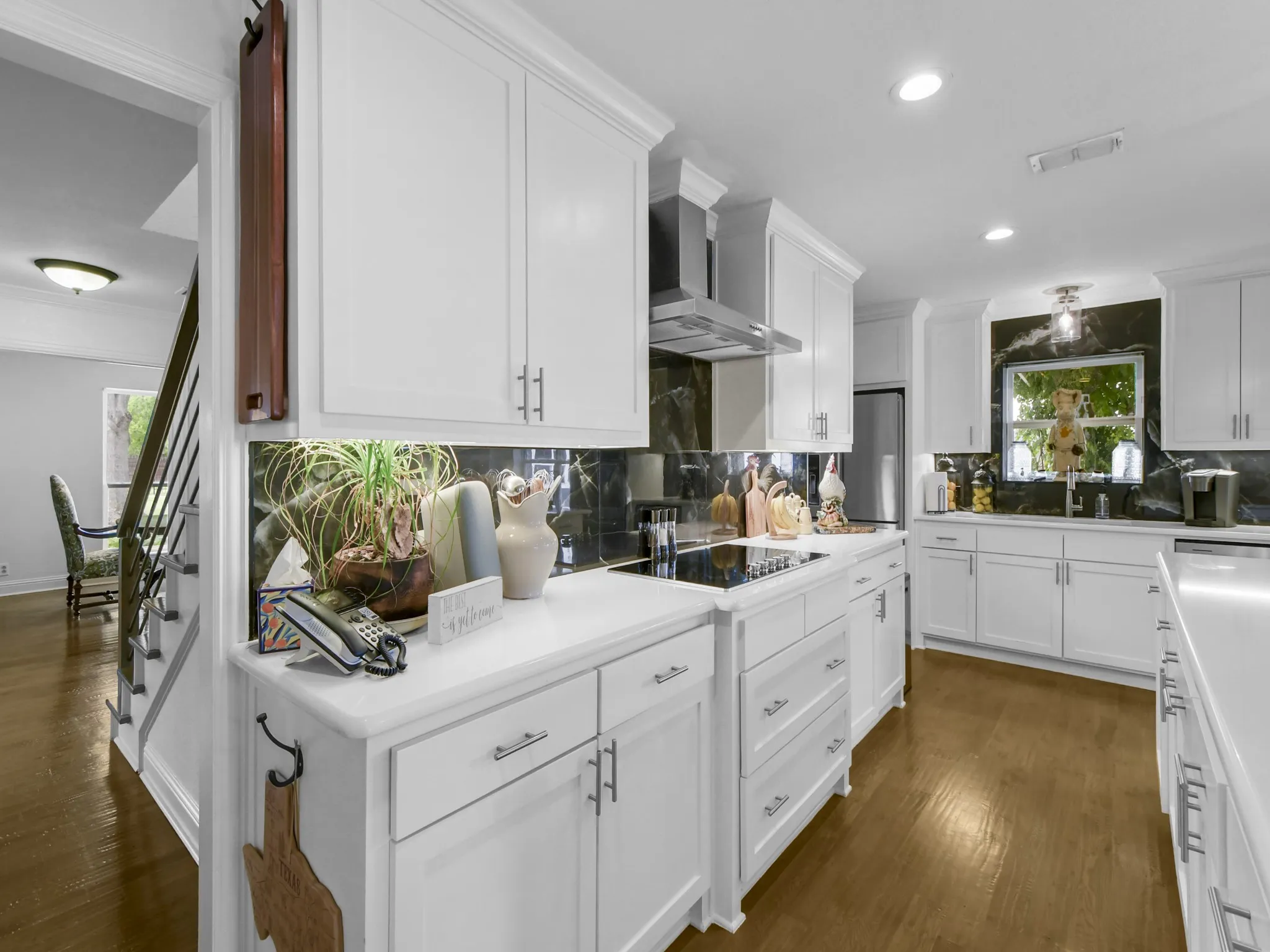 Gourmet kitchen featuring white cabinetry, light-toned countertops, dark stone backsplash, recessed lighting, and wood-finish flooring