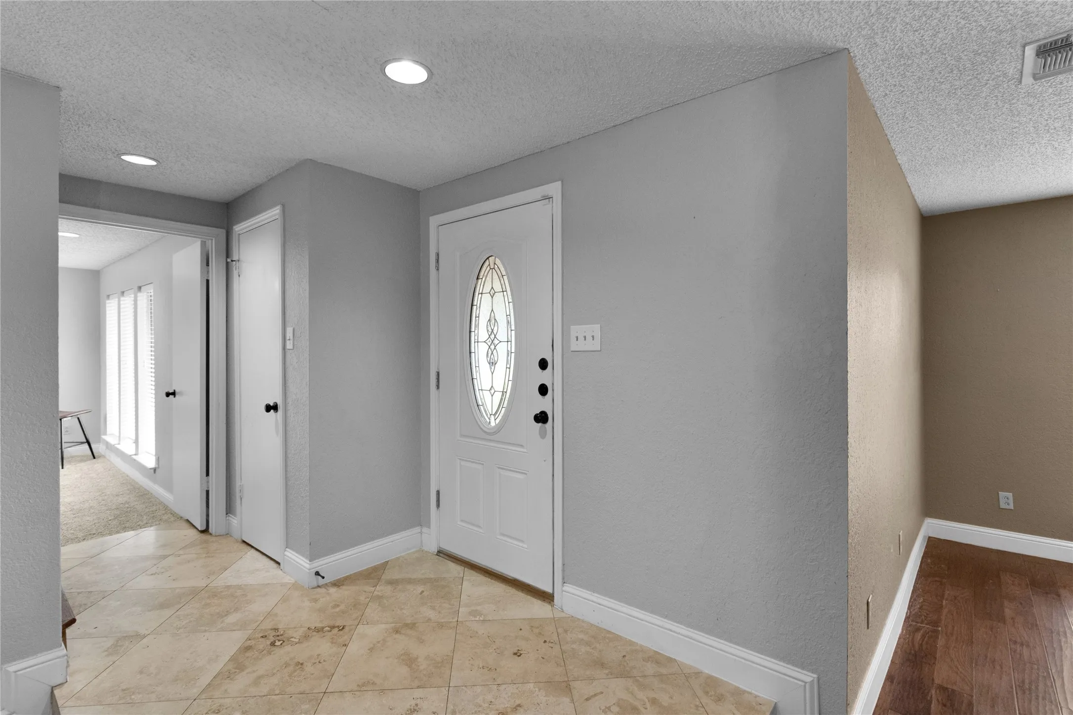 Entryway featuring a white door with an oval decorative glass insert, recessed lighting, and tile flooring