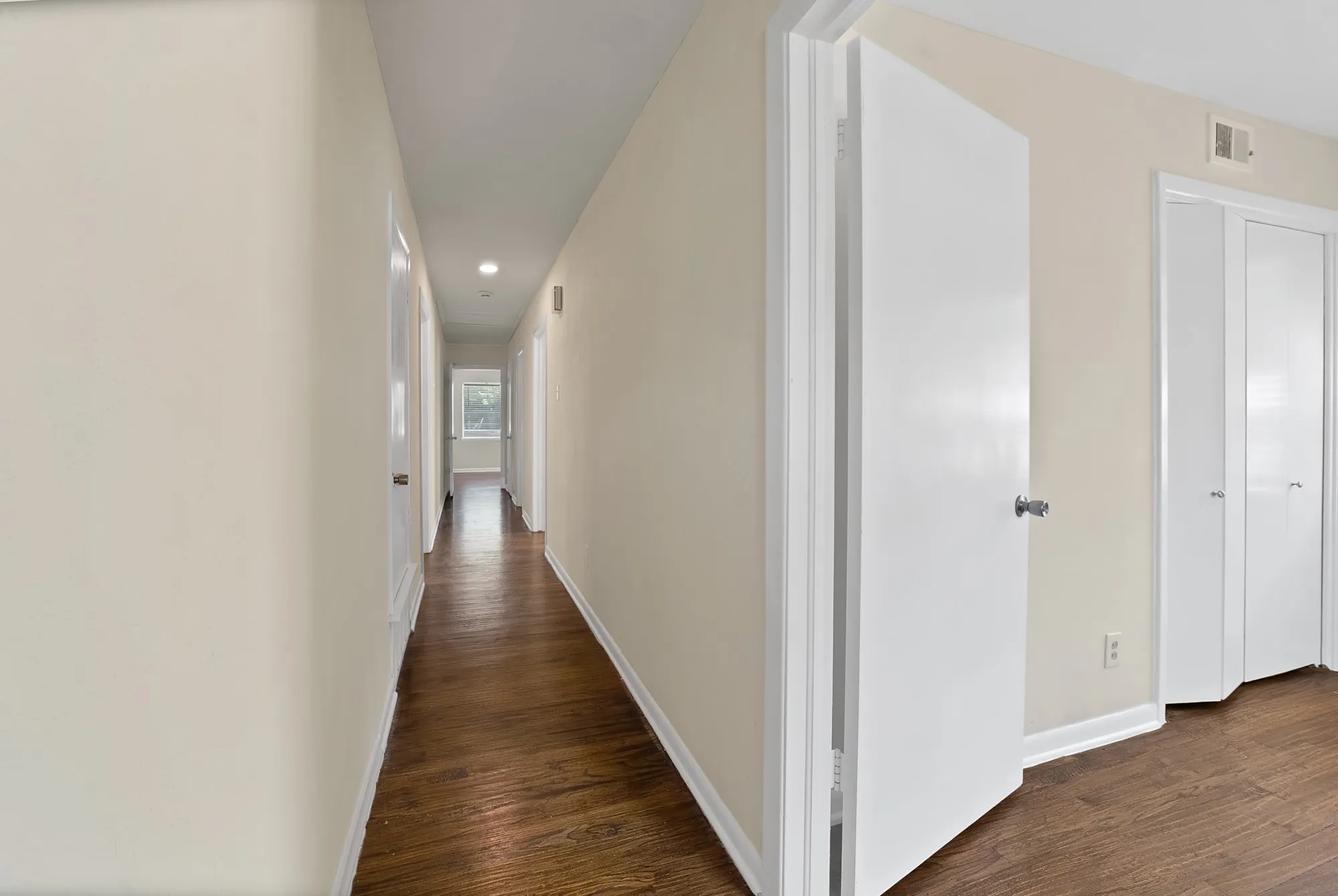 Hallway featuring wood-finish flooring, light-toned wall paint, recessed lighting, and white baseboards