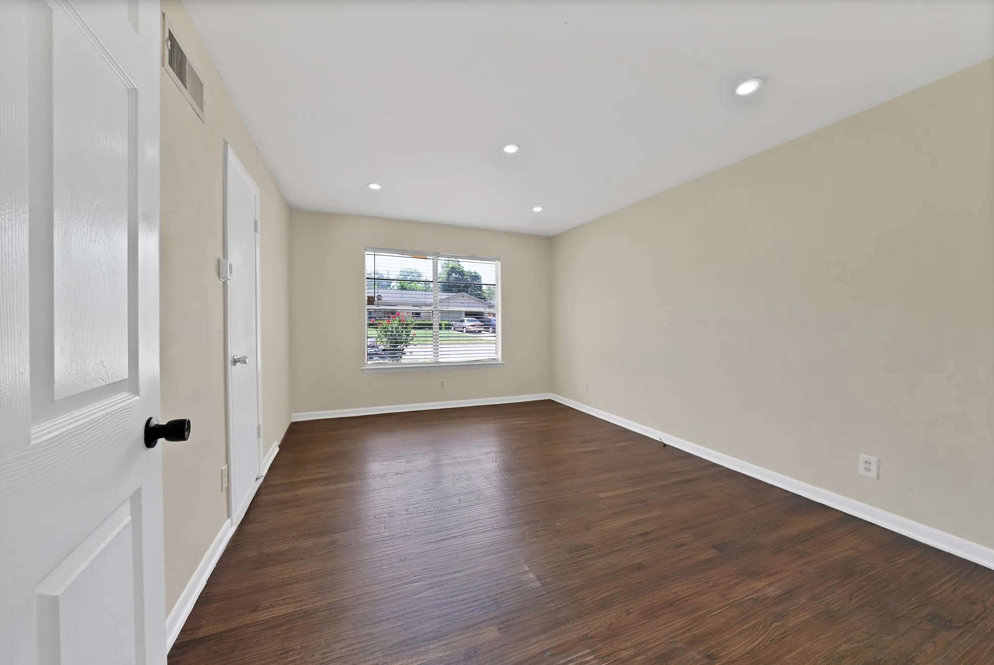 Expansive room featuring rich wood-finish flooring, recessed lighting, and a neutral wall palette