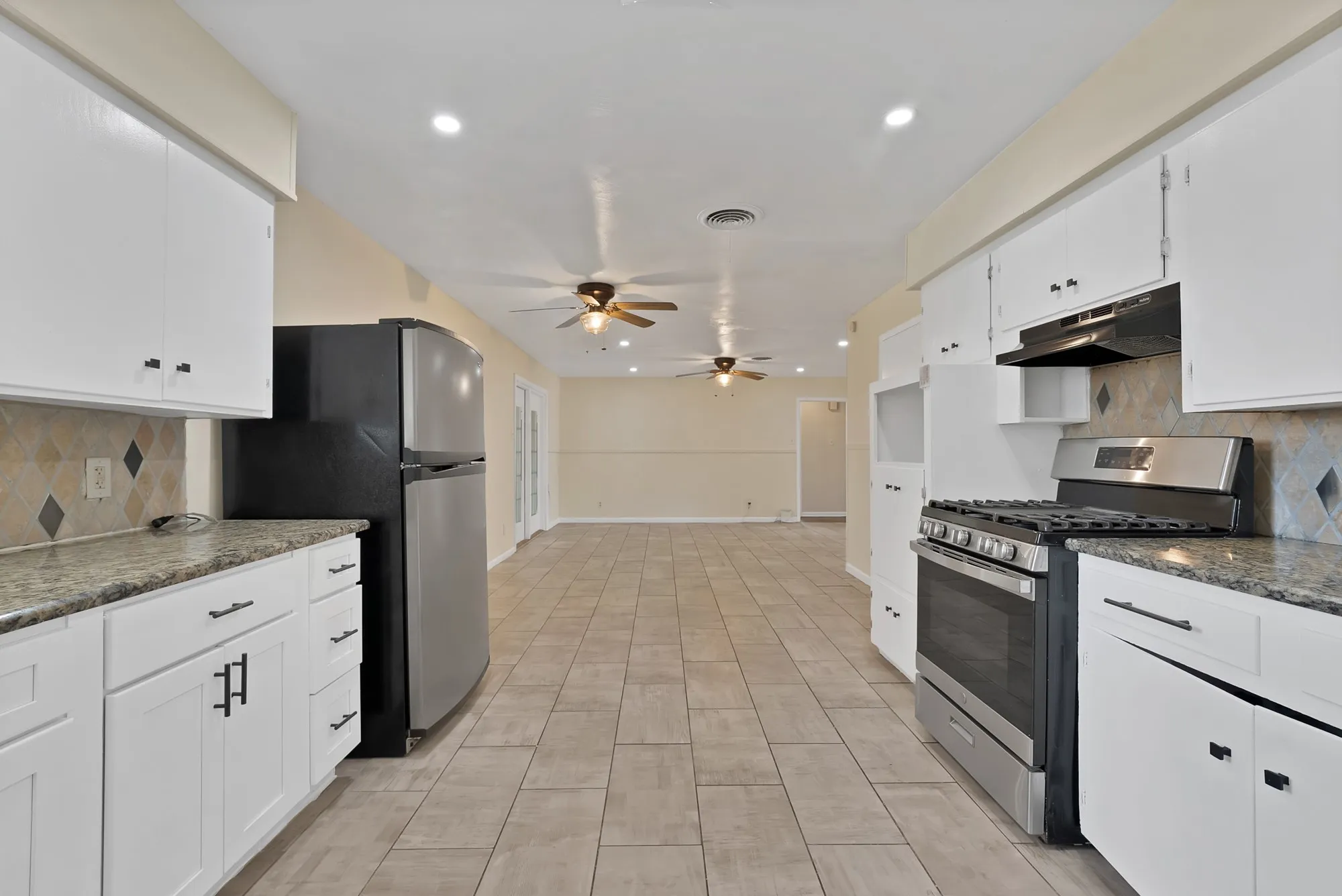 Kitchen featuring white cabinetry, granite-finish countertops, and a patterned tile backsplash