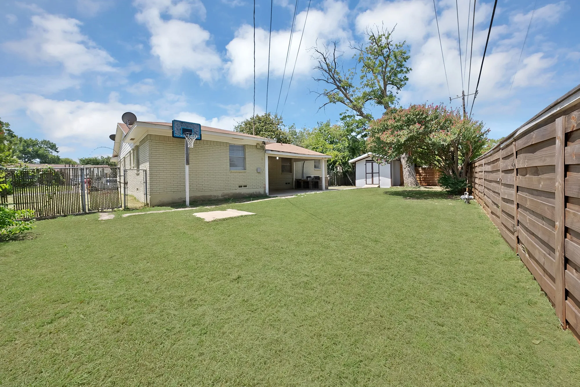 Expansive backyard featuring a lush lawn, privacy fencing, and a detached storage shed