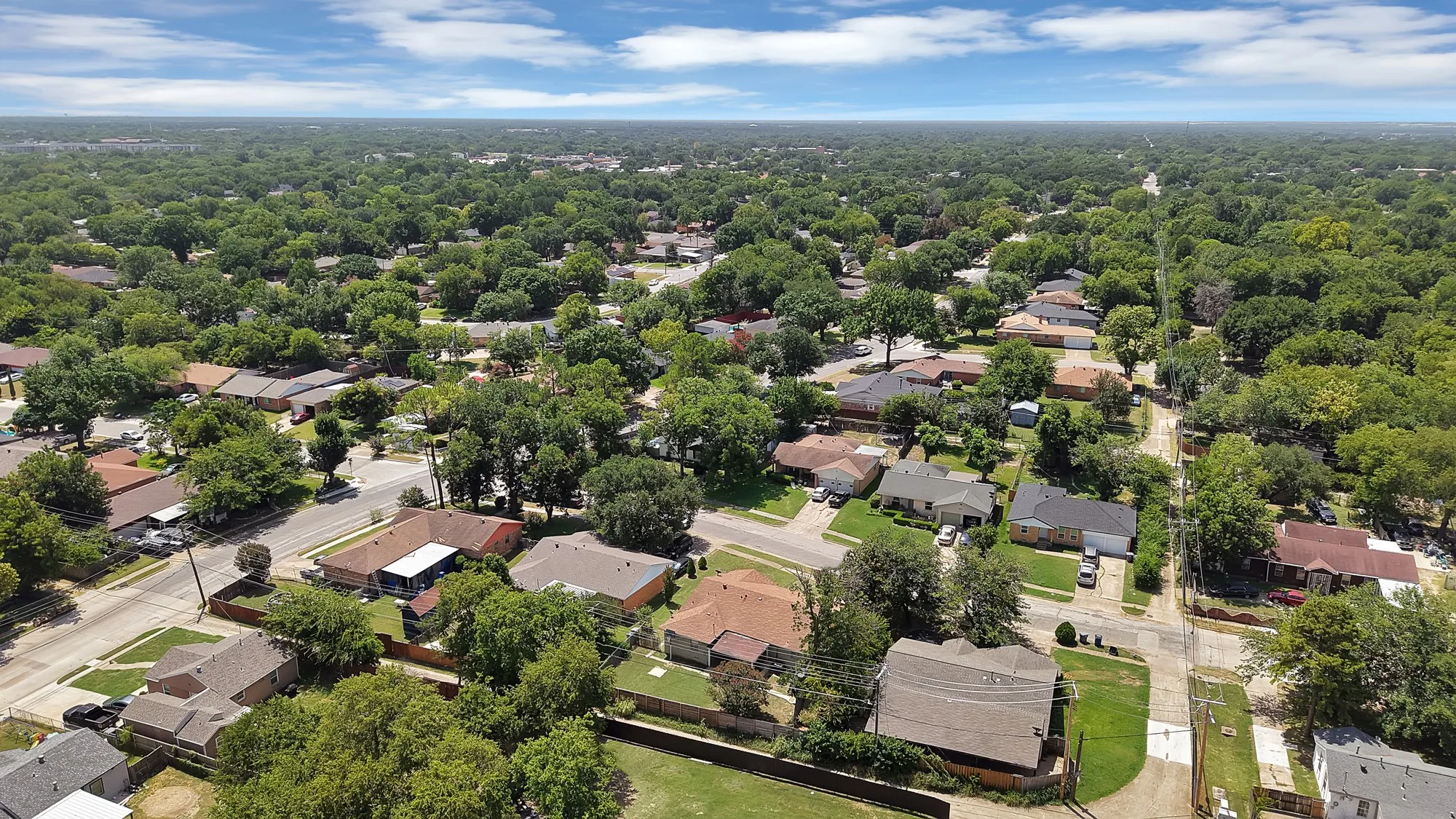 Expansive aerial perspective showcasing a residential neighborhood with abundant mature trees and a dense tree canopy