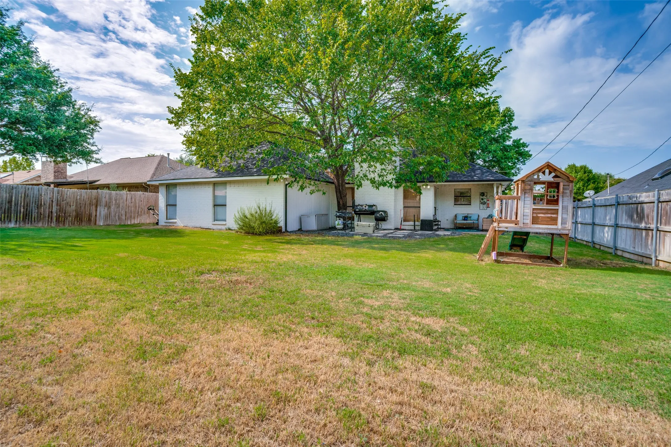 Expansive backyard featuring a manicured lawn, mature trees, and privacy fencing
