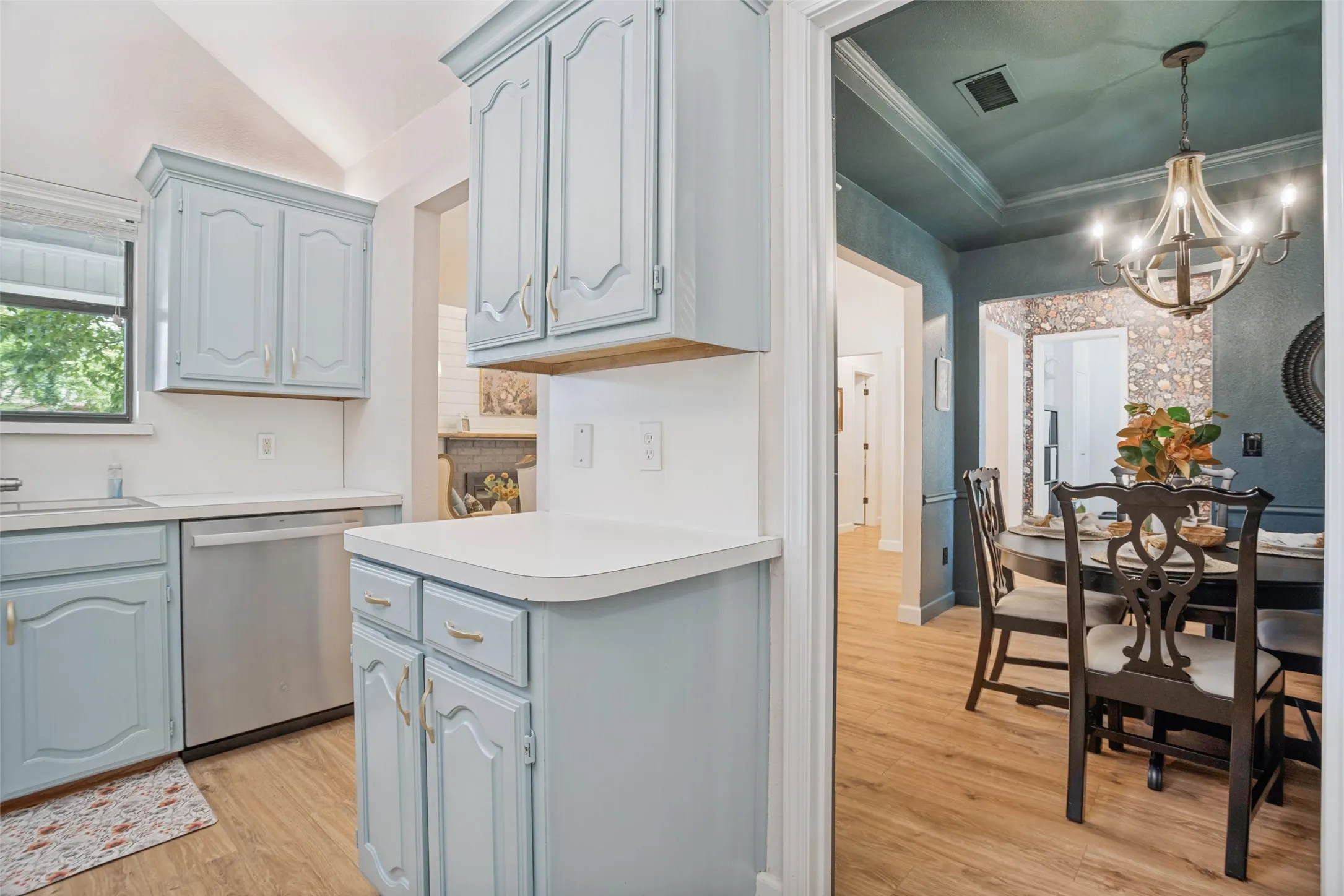 Kitchen featuring light blue cabinetry, white countertops, a stainless steel dishwasher, and wood-finish flooring