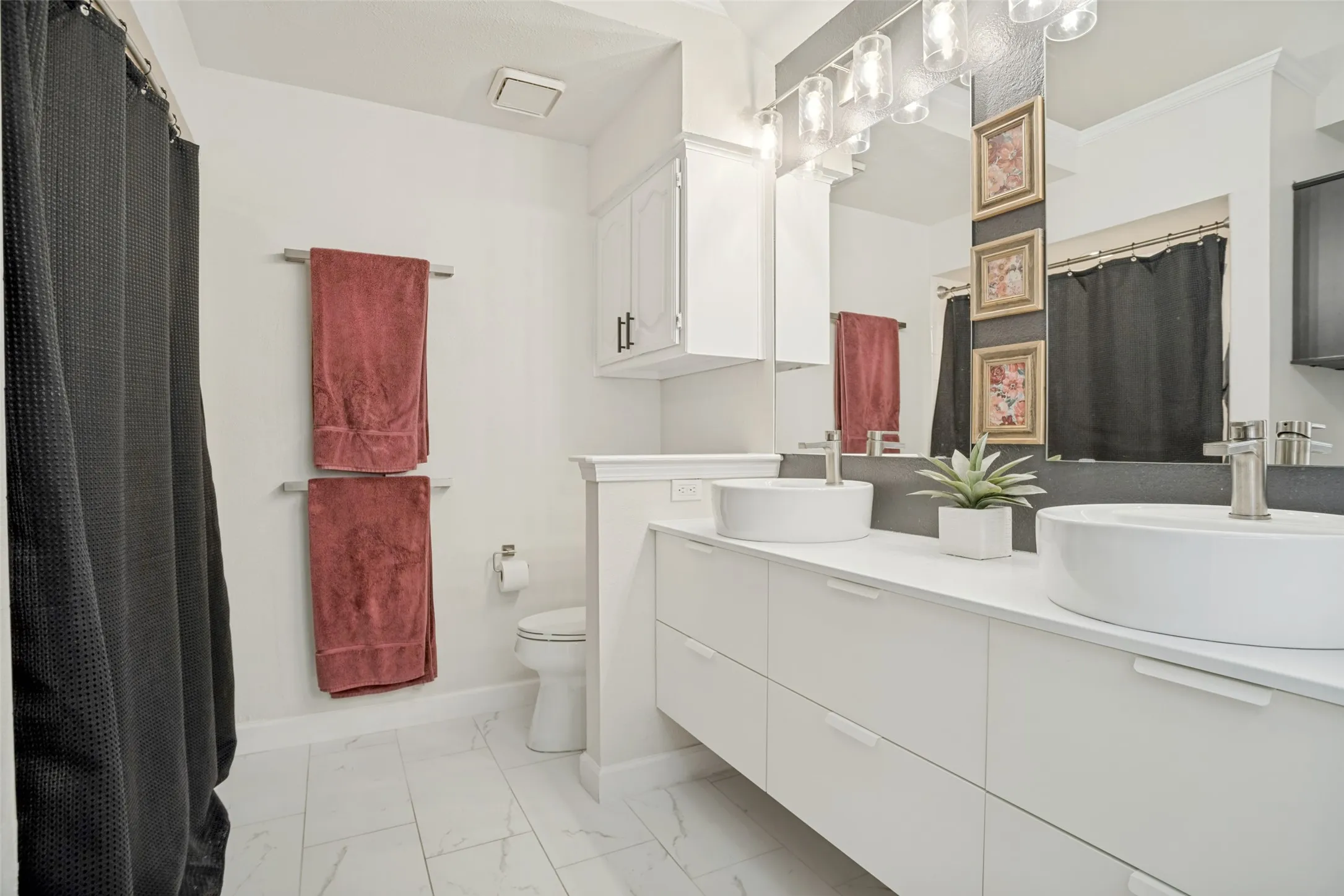 Spacious bath featuring dual vessel sinks, white cabinetry, a large mirror, chrome fixtures, and tile flooring