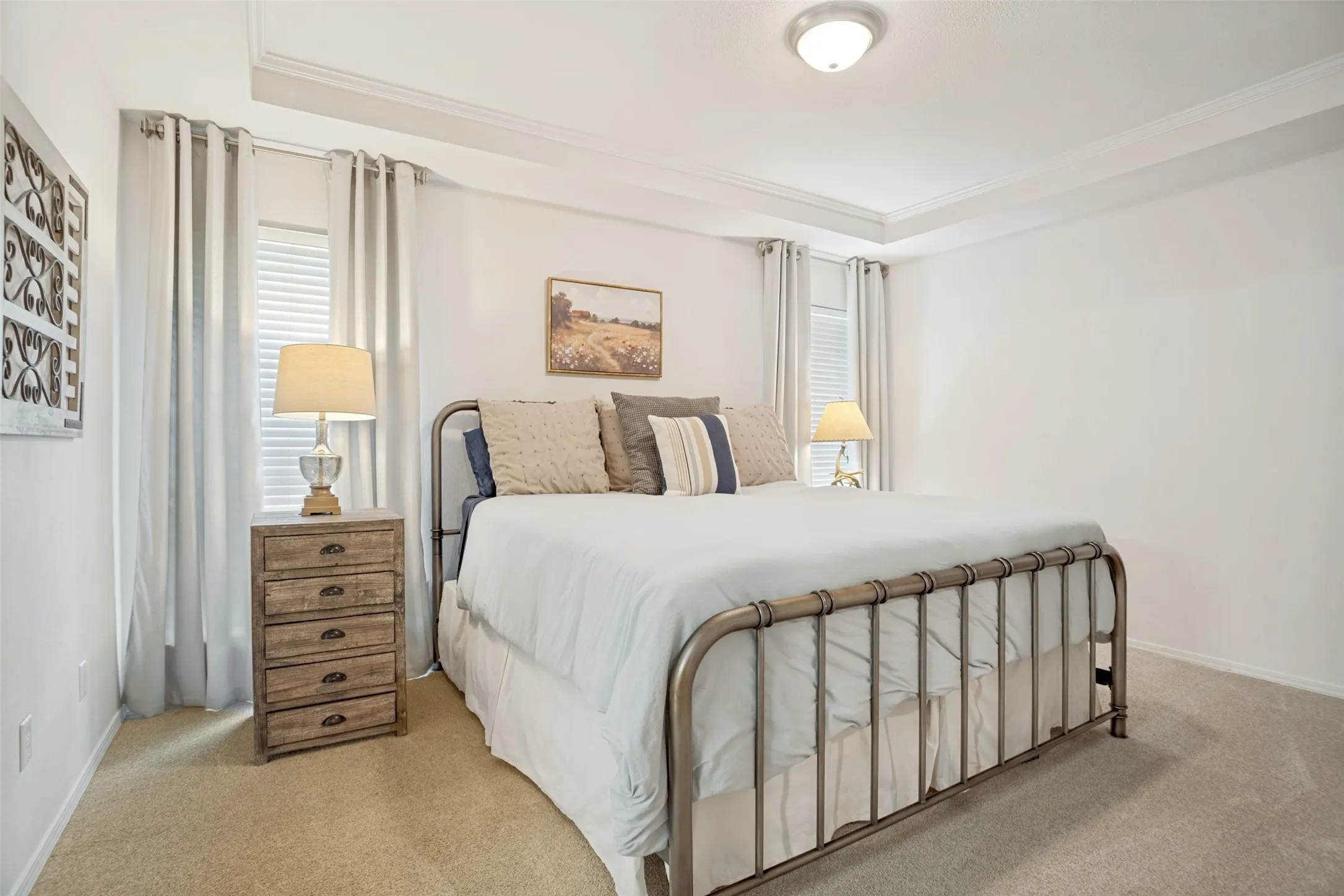 Bedroom featuring a tray ceiling with crown molding, carpet flooring, and two windows with blinds