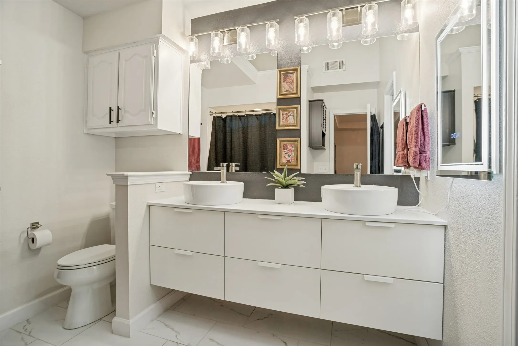 Double vanity with white vessel sinks, a wall-mounted light fixture, and a large mirror
