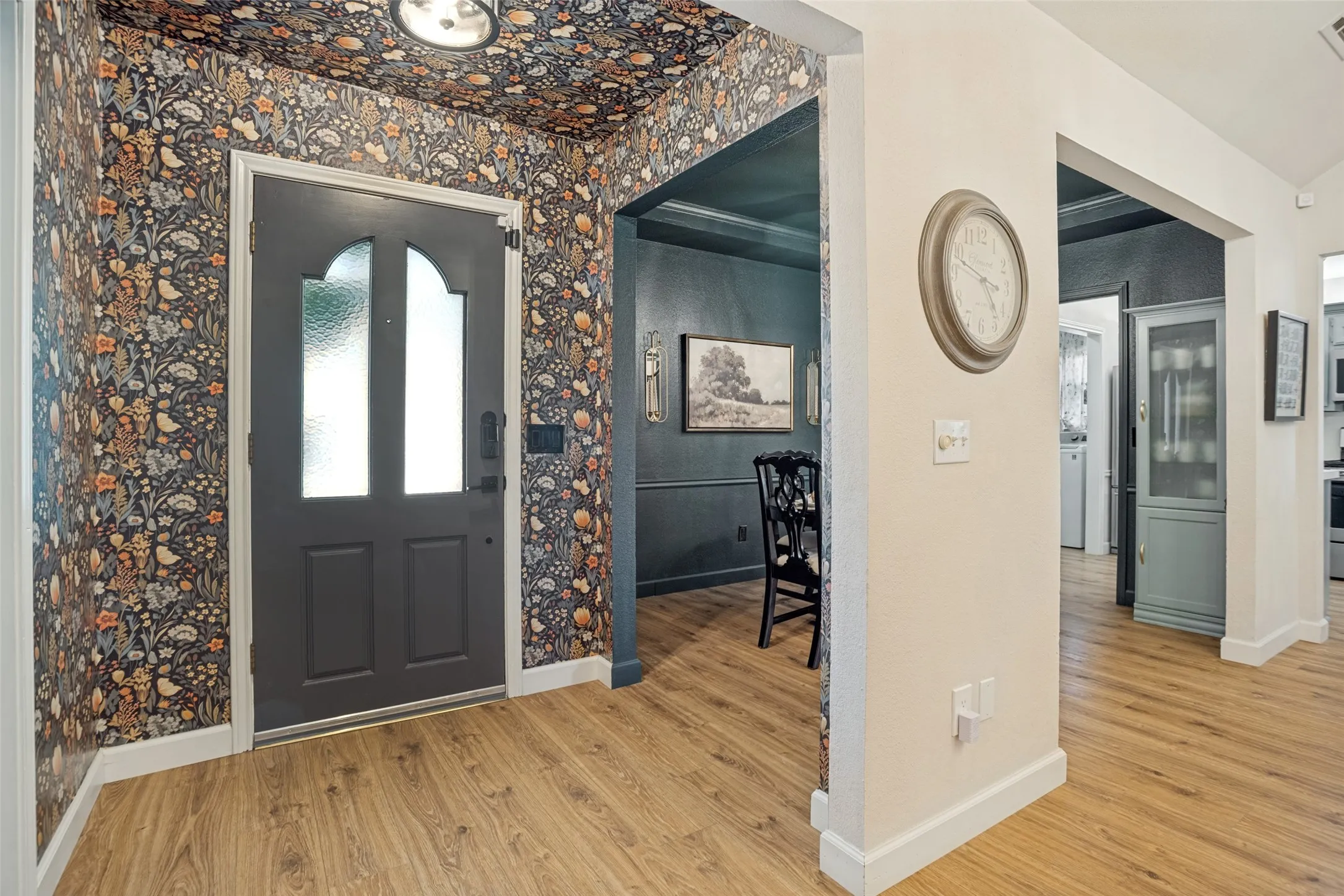 Entryway with patterned wallpaper, wood-finish flooring, and a contemporary ceiling light fixture