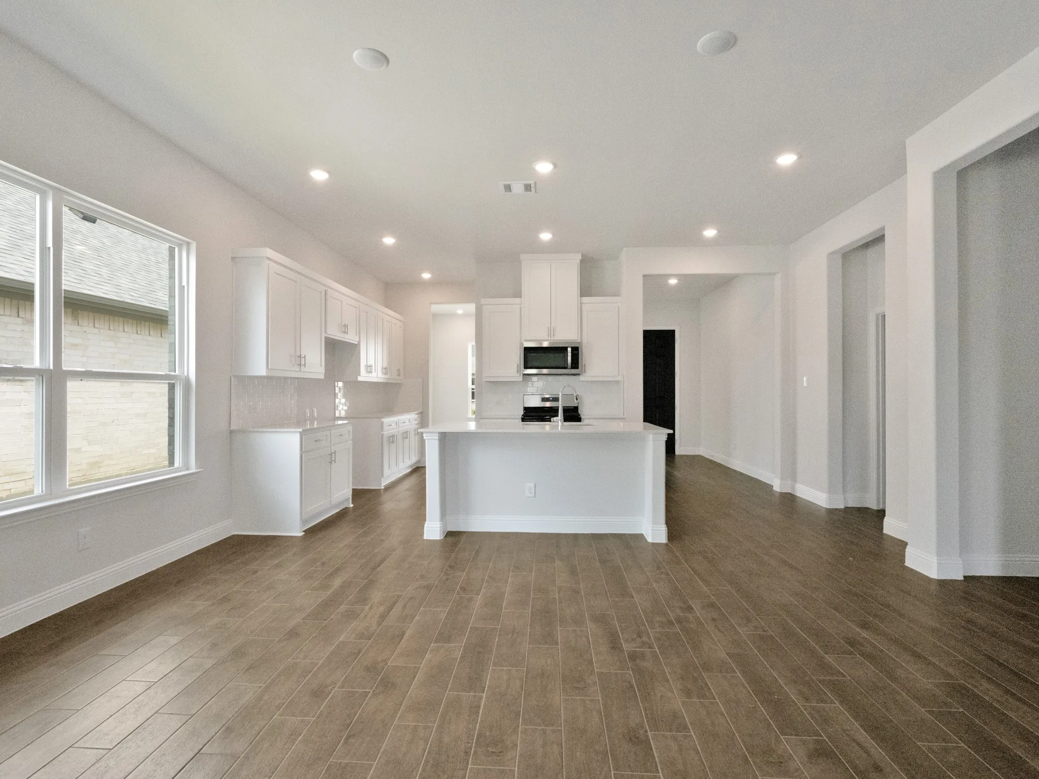 Kitchen featuring white cabinetry, a kitchen island with sink, stainless steel appliances, recessed lighting, and tasteful backsplash