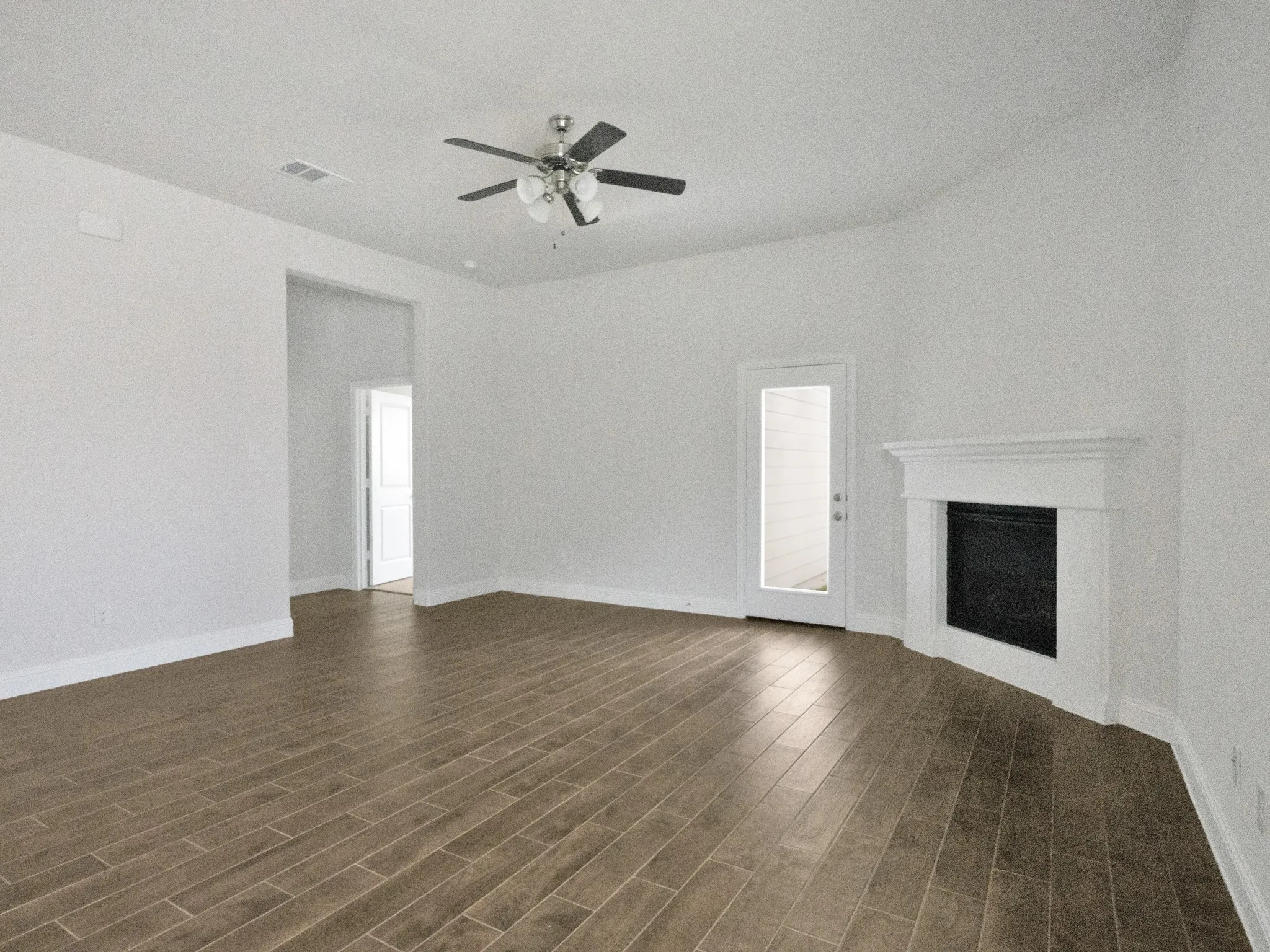 Unfurnished living room featuring a fireplace, dark wood-style floors, and ceiling fan