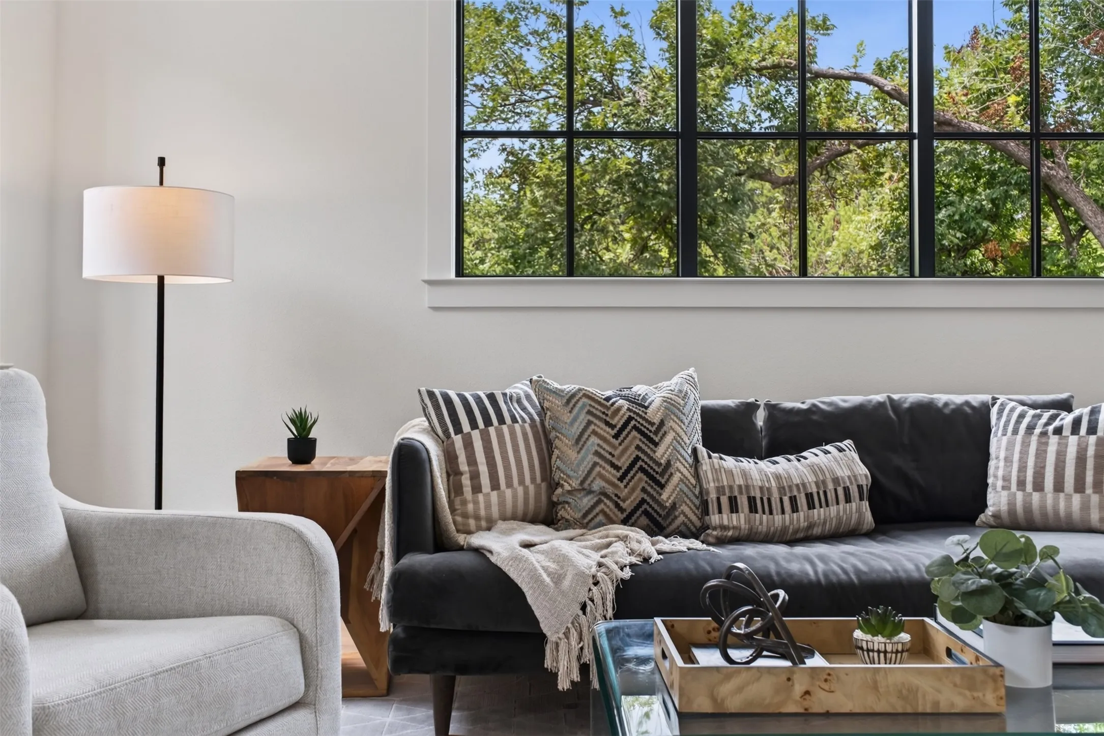 Spacious living area featuring a large picture window with black grid panes, white trim, and abundant natural light