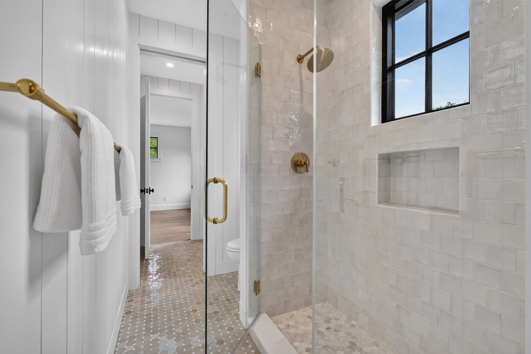 Spacious walk-in shower with clear glass enclosure and brass hardware
