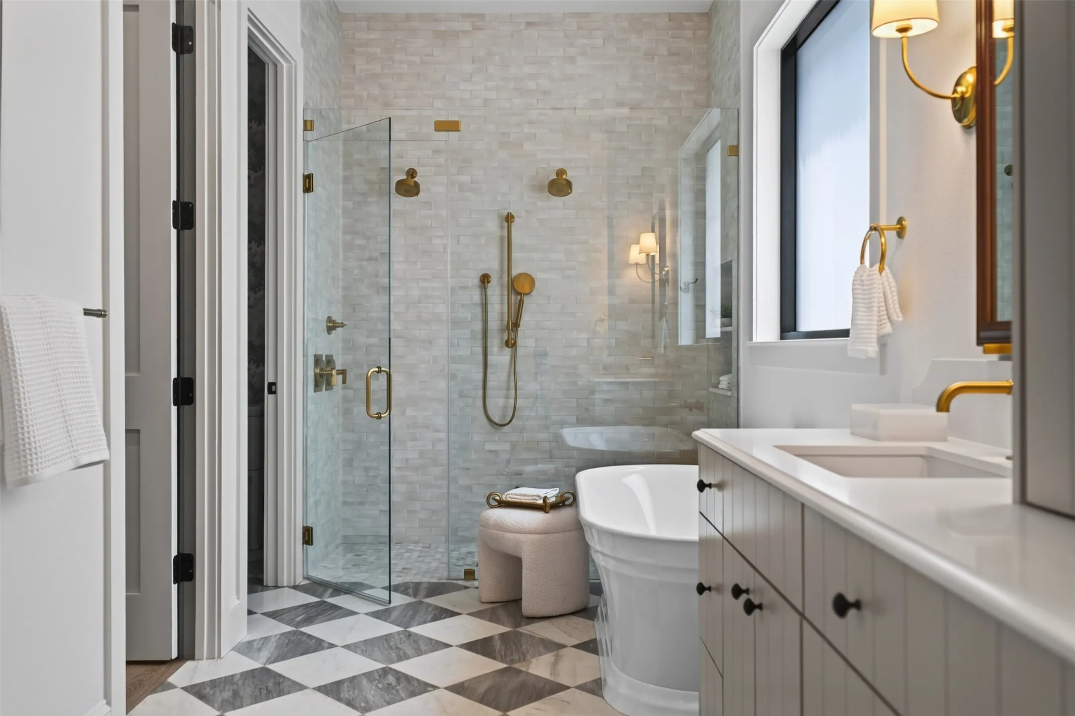 Bathroom featuring a glass-enclosed shower with gold-tone fixtures, a freestanding soaking tub, a single vanity with an integrated sink and gold-tone faucet, and checkerboard floor tiling