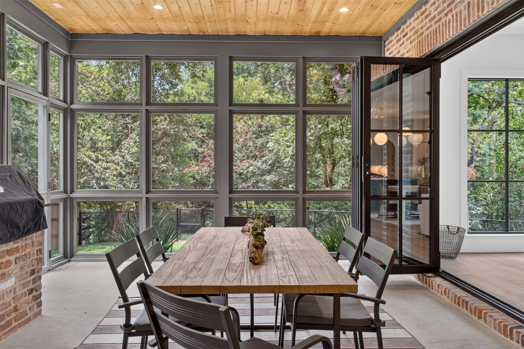 Screened porch featuring a wood-plank ceiling, concrete flooring, and extensive multi-pane windows