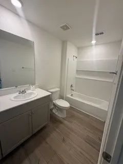 Bathroom featuring a single vanity with storage, wood-finish flooring, recessed lighting, and a combination tub and shower