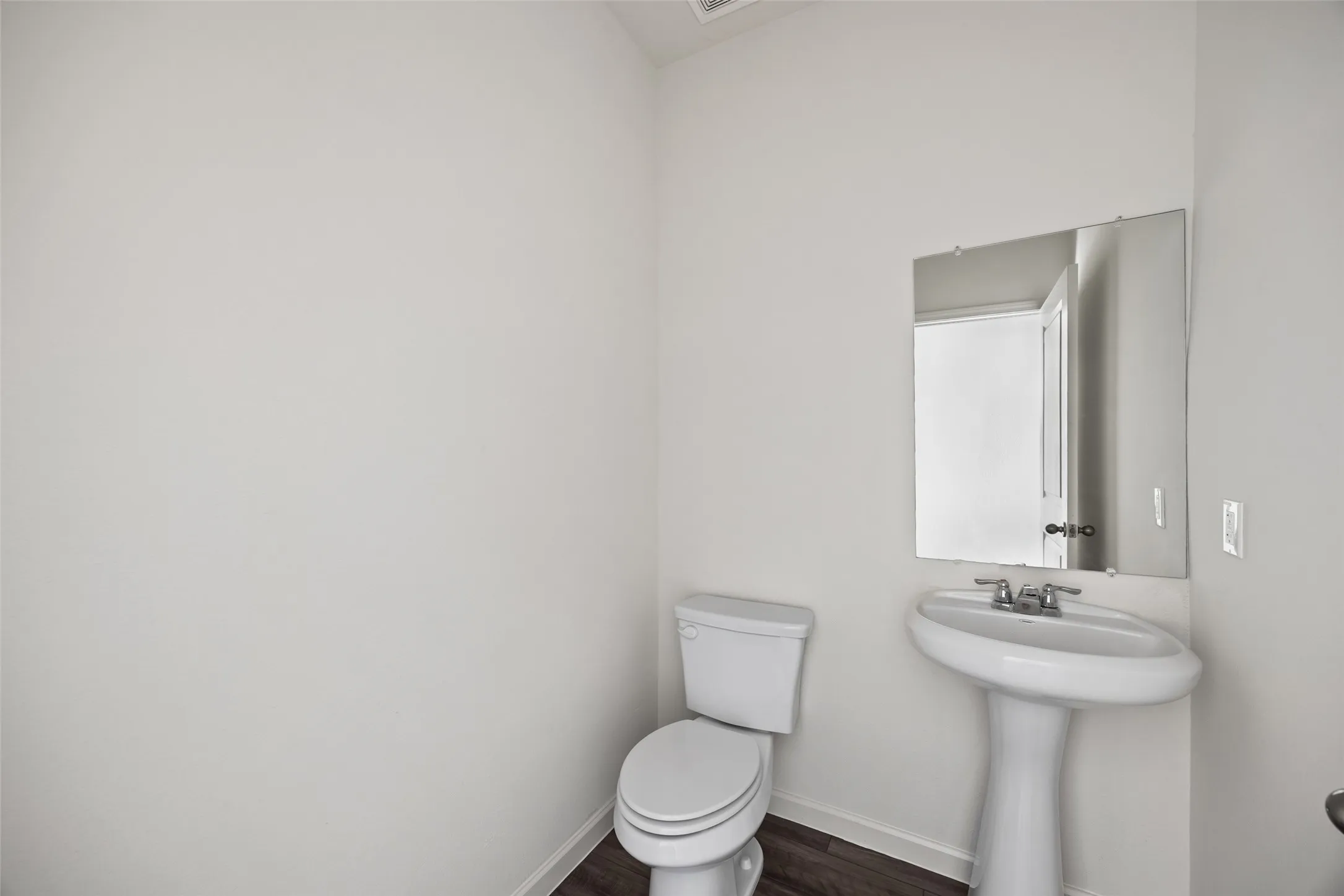 Pedestal sink with chrome faucet and rectangular wall-mounted mirror