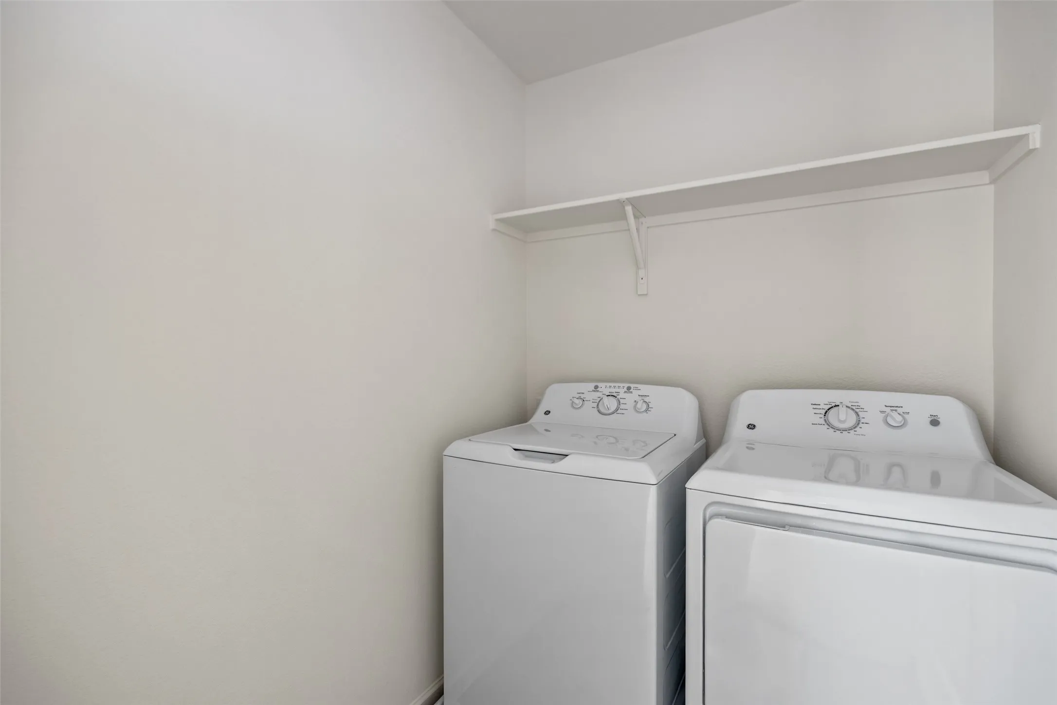 Dedicated laundry space featuring a white shelf with support brackets