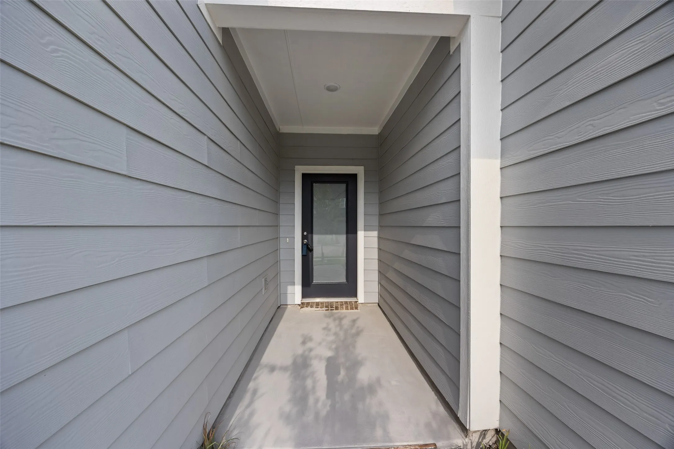 Covered entry with gray horizontal siding and contrasting white trim