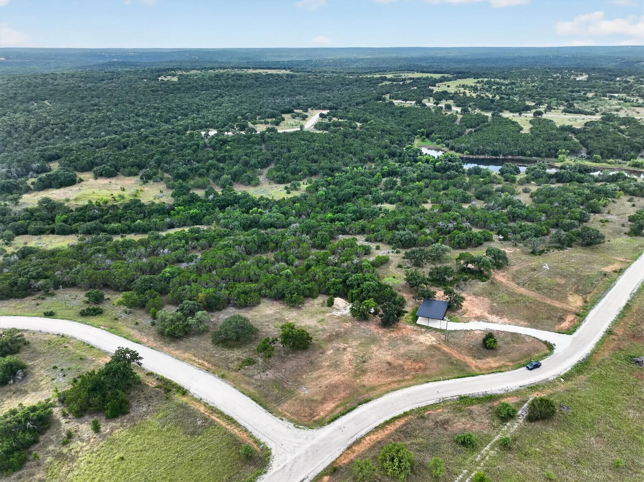 Extensive natural landscape featuring a winding river, dense tree cover, and a prominent unpaved road network