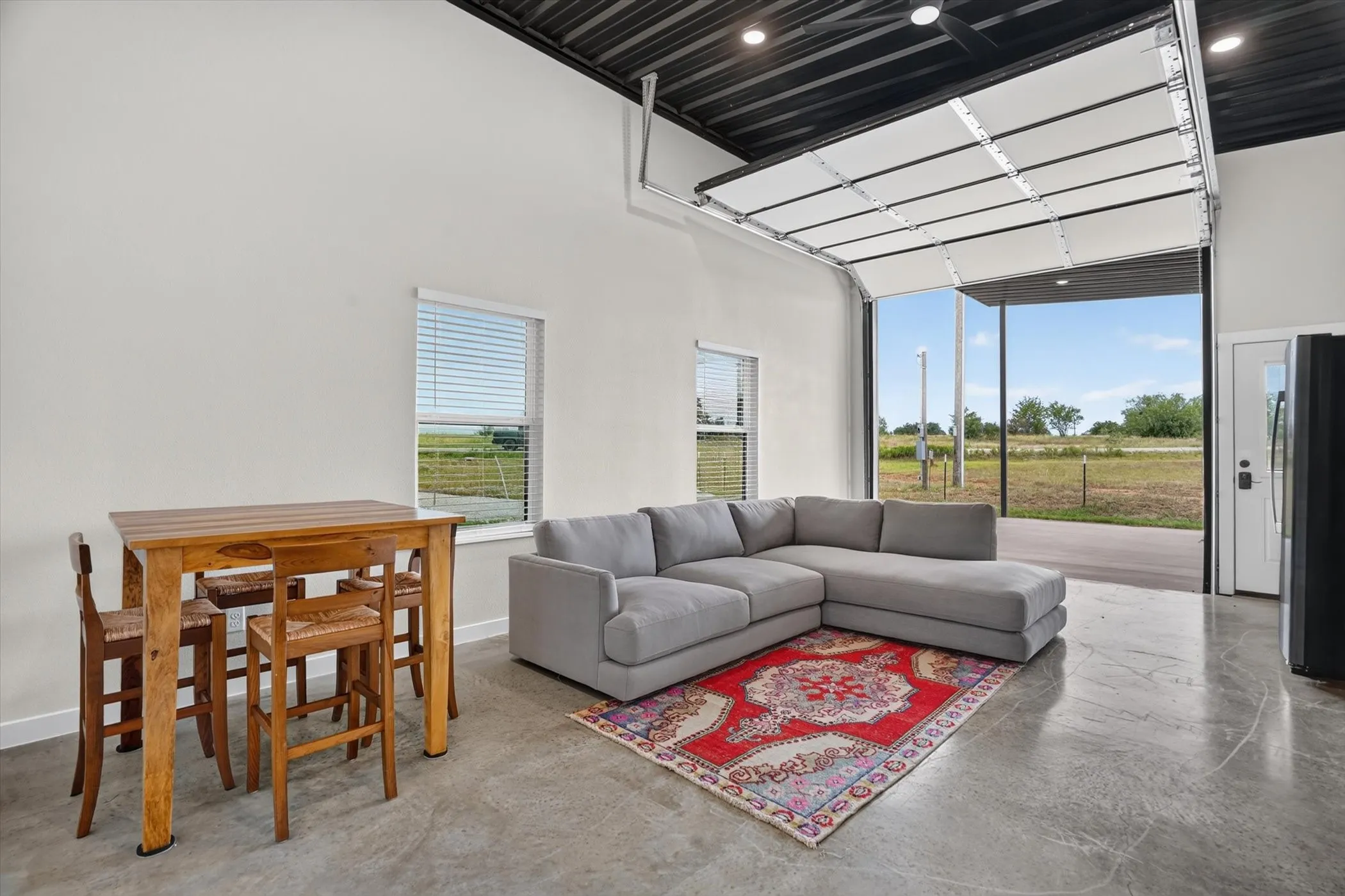 Open-concept room featuring a roll-up garage door, high ceilings, and polished concrete flooring
