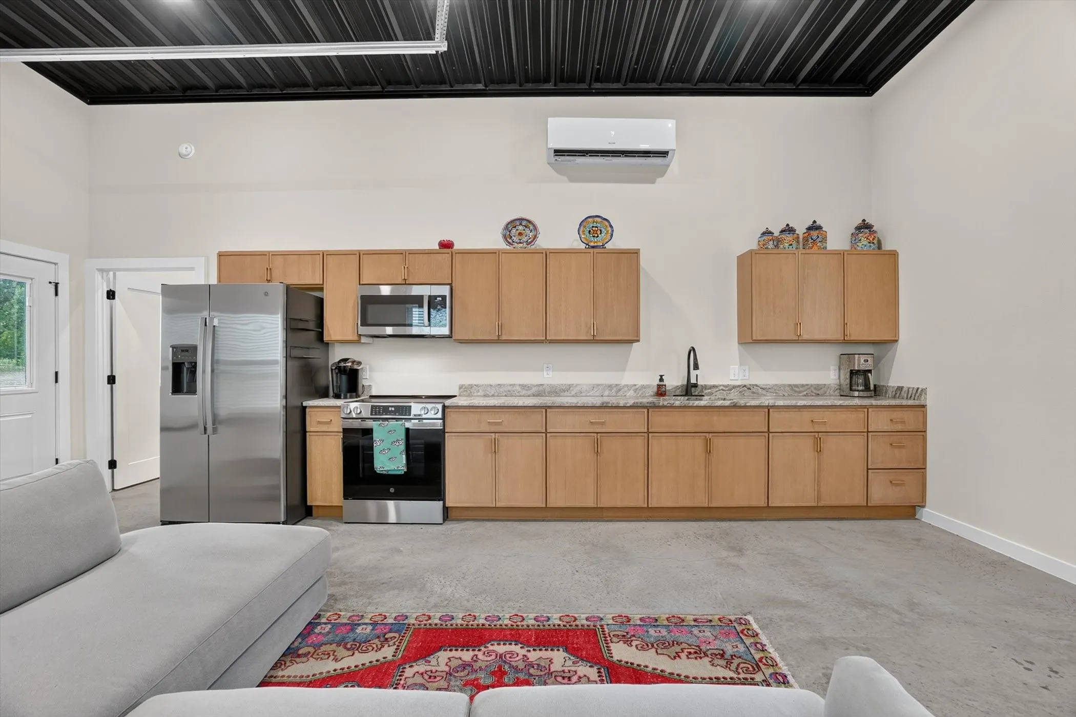 Kitchenette featuring light wood-finish cabinetry, stainless steel appliances, and a granite-style countertop