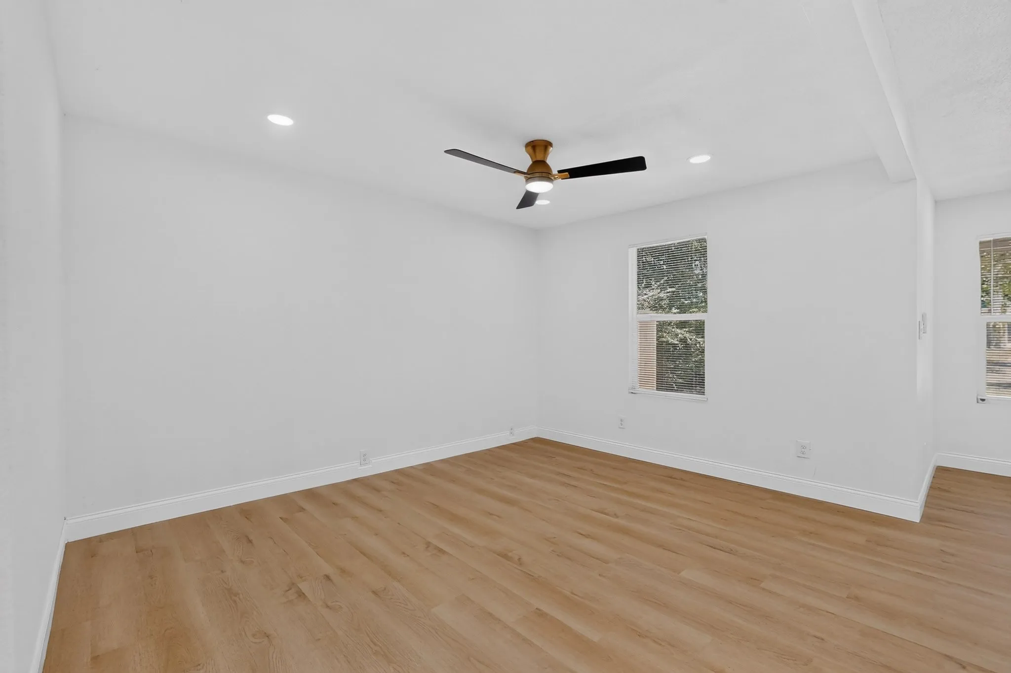 Spacious room featuring wood-finish flooring, recessed lighting, and a contemporary ceiling fan