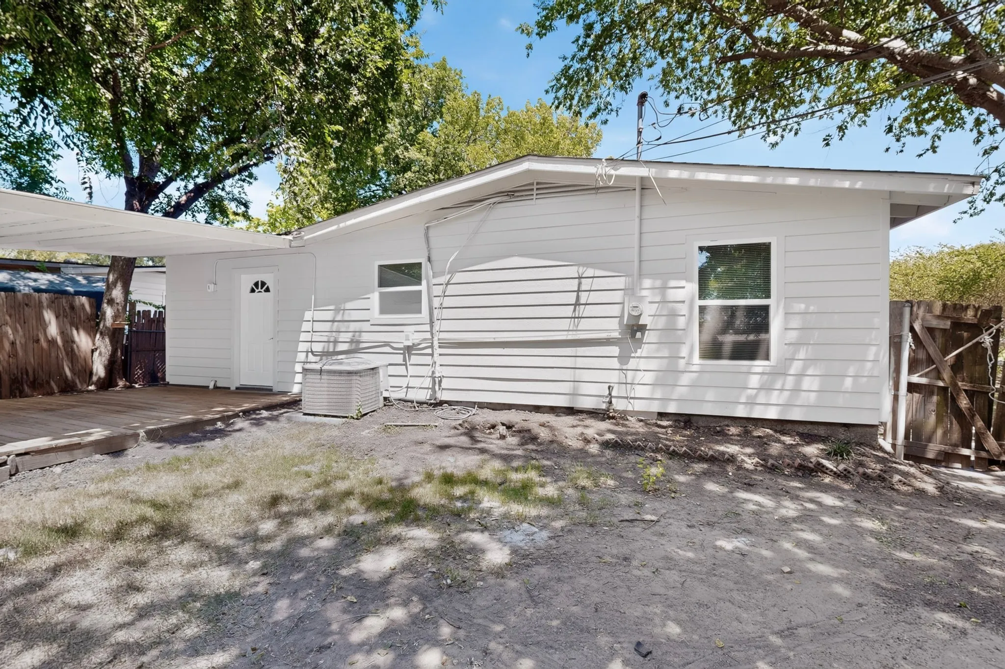 Rear exterior featuring white horizontal siding, a covered deck, and a fenced perimeter