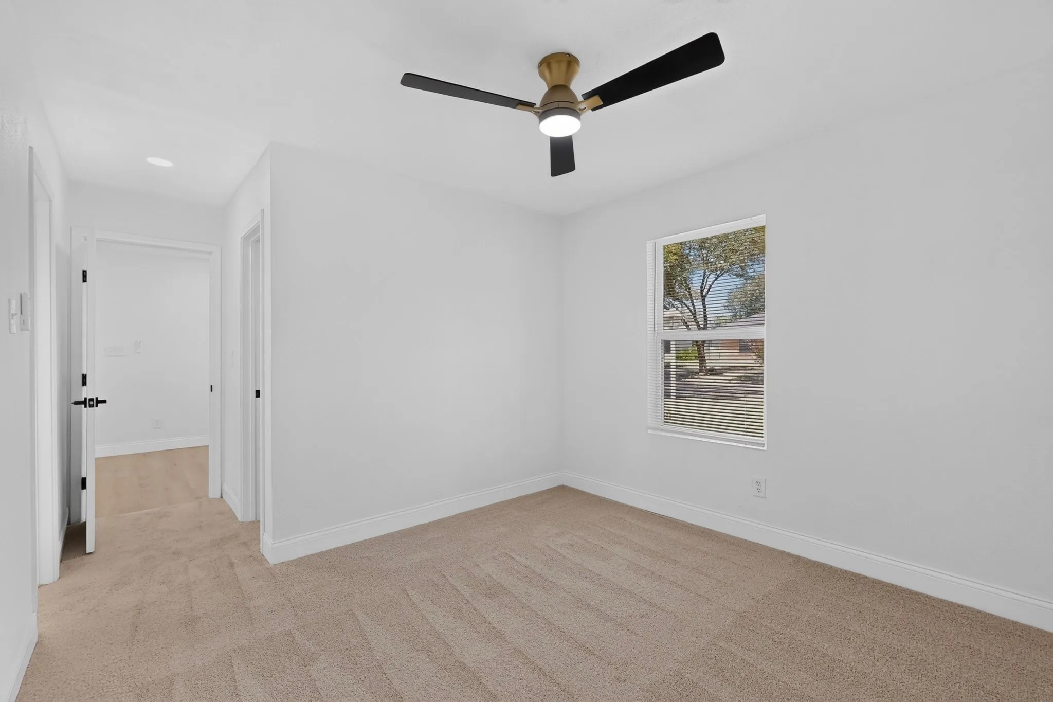 Room featuring a contemporary ceiling fan with integrated lighting, a single window with blinds, pristine white walls, and neutral-toned carpeting and private bath and walk in closet