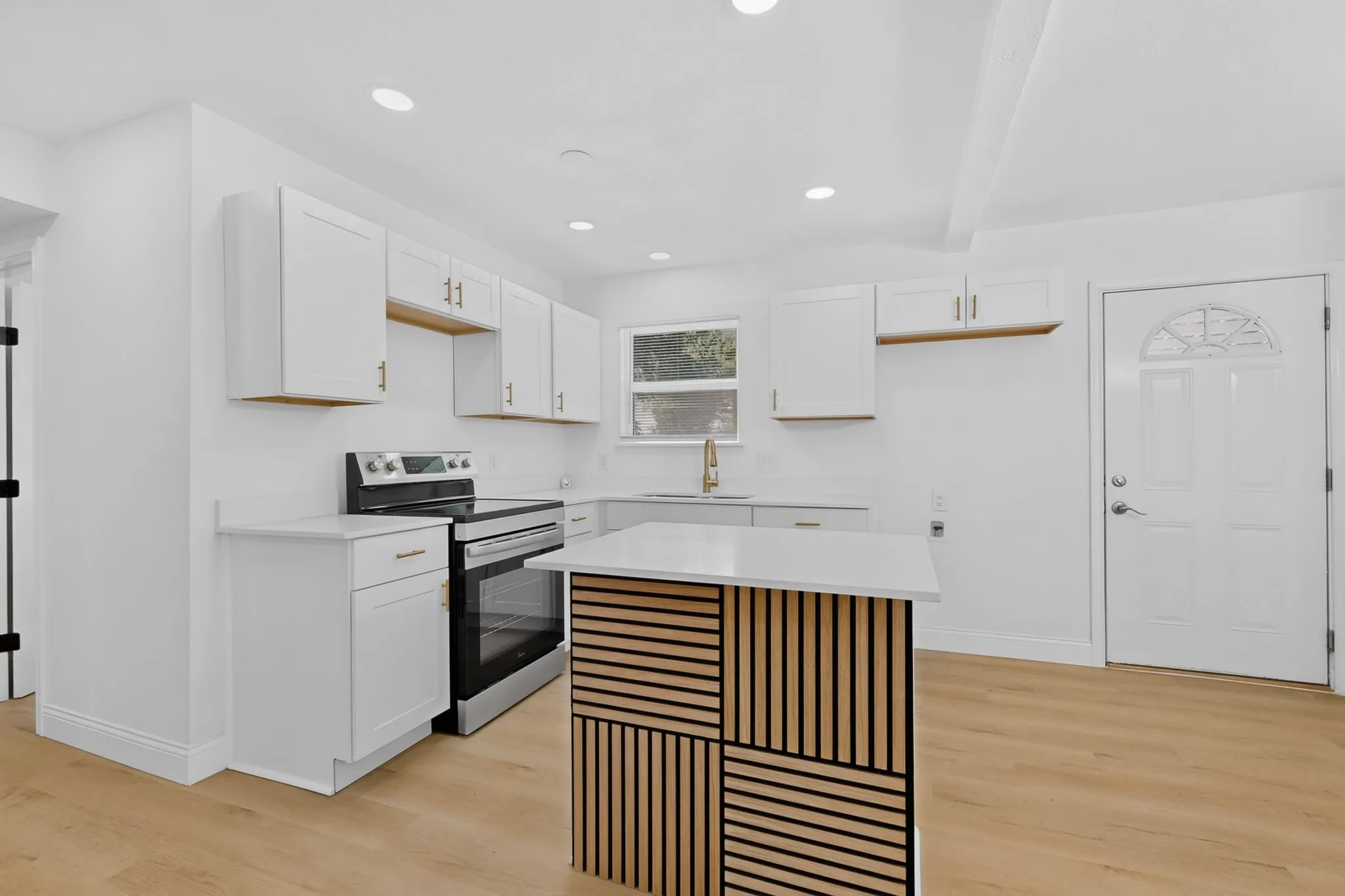 Kitchen with white shaker cabinetry, stainless steel range, and a central island featuring a wood-slat design