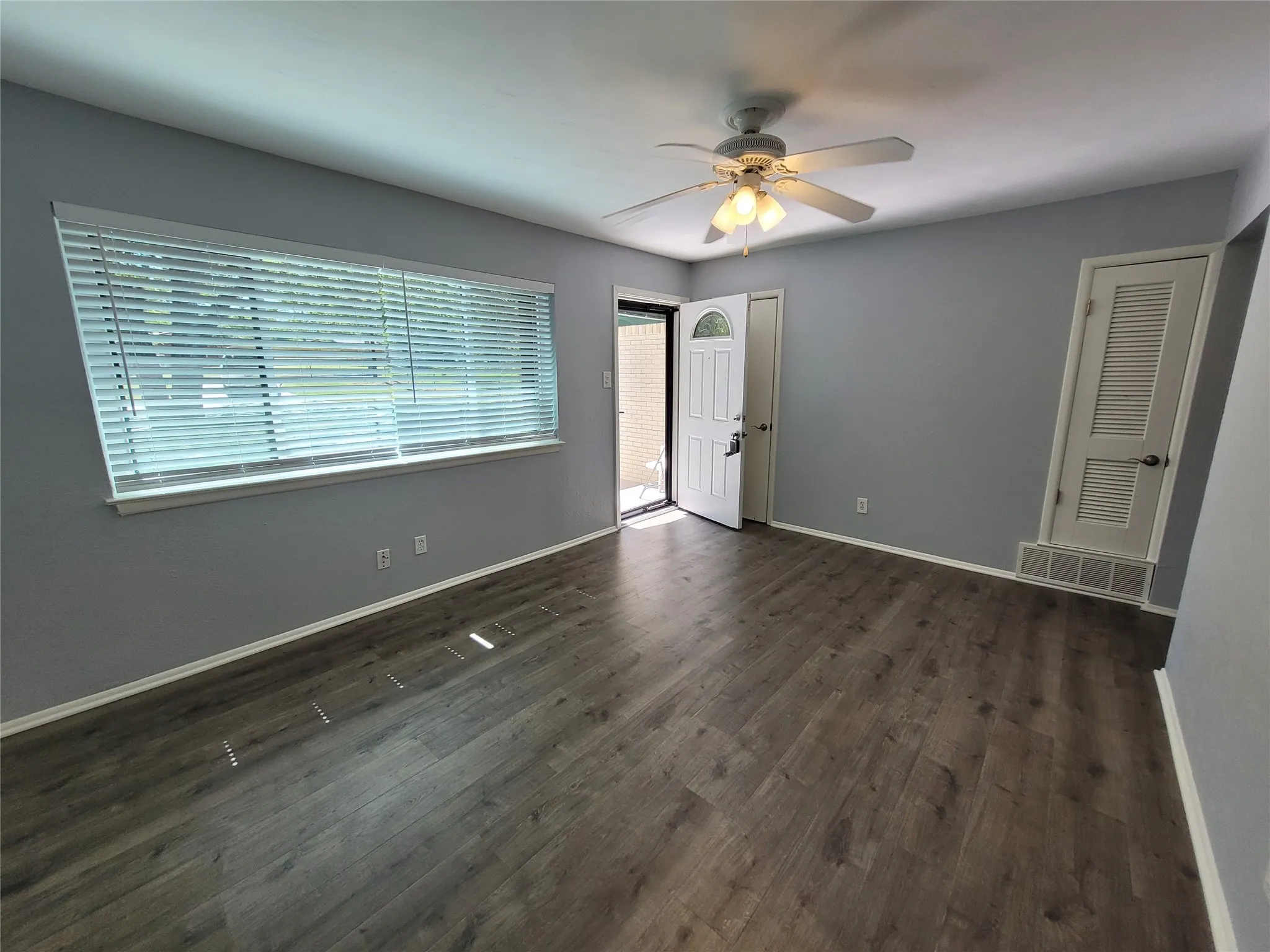 Wood look flooring, big picture window, and ceiling fan in formal living area.