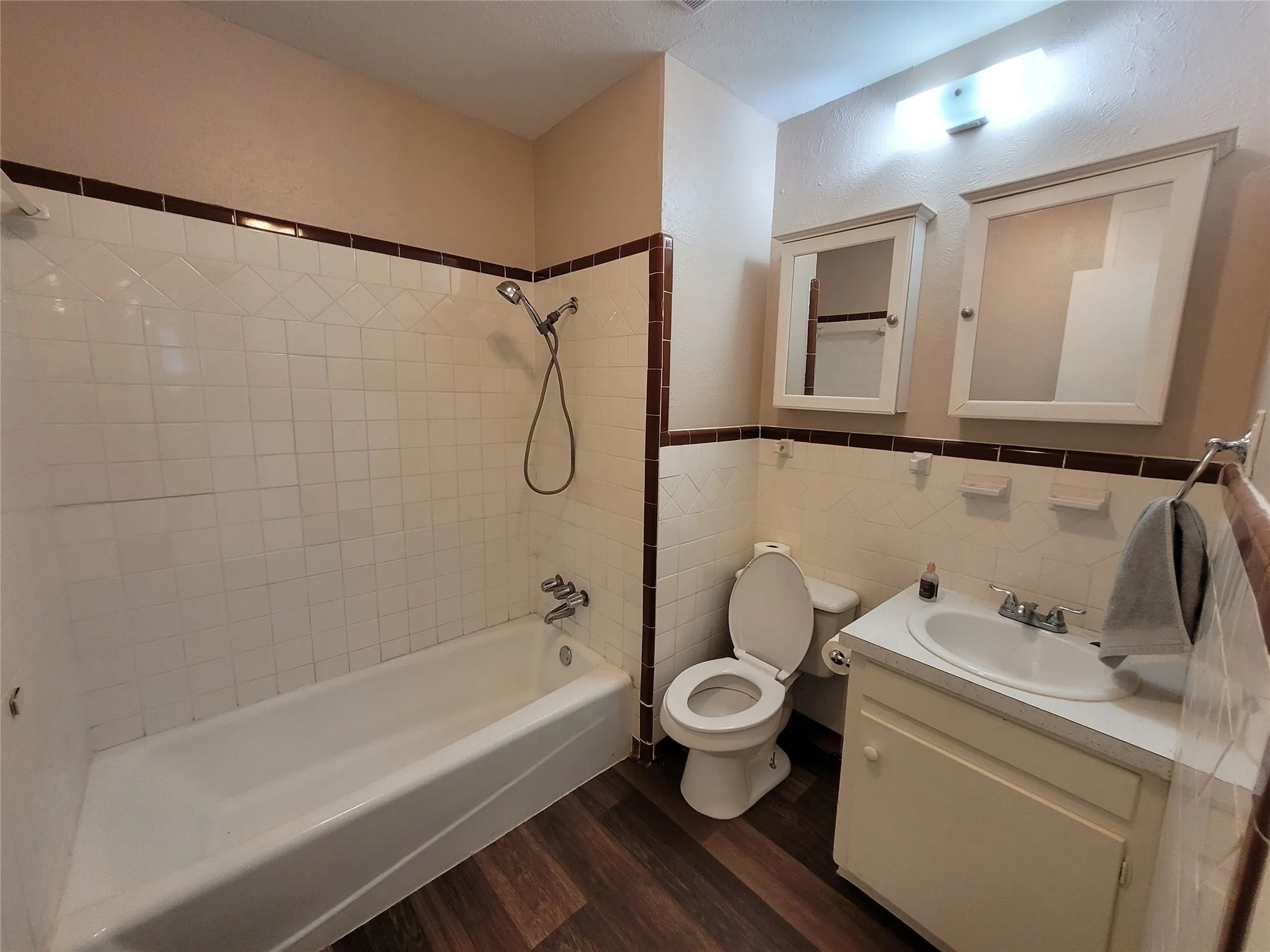 Tub and shwer combination with tile surround plus two medicine cabinets.