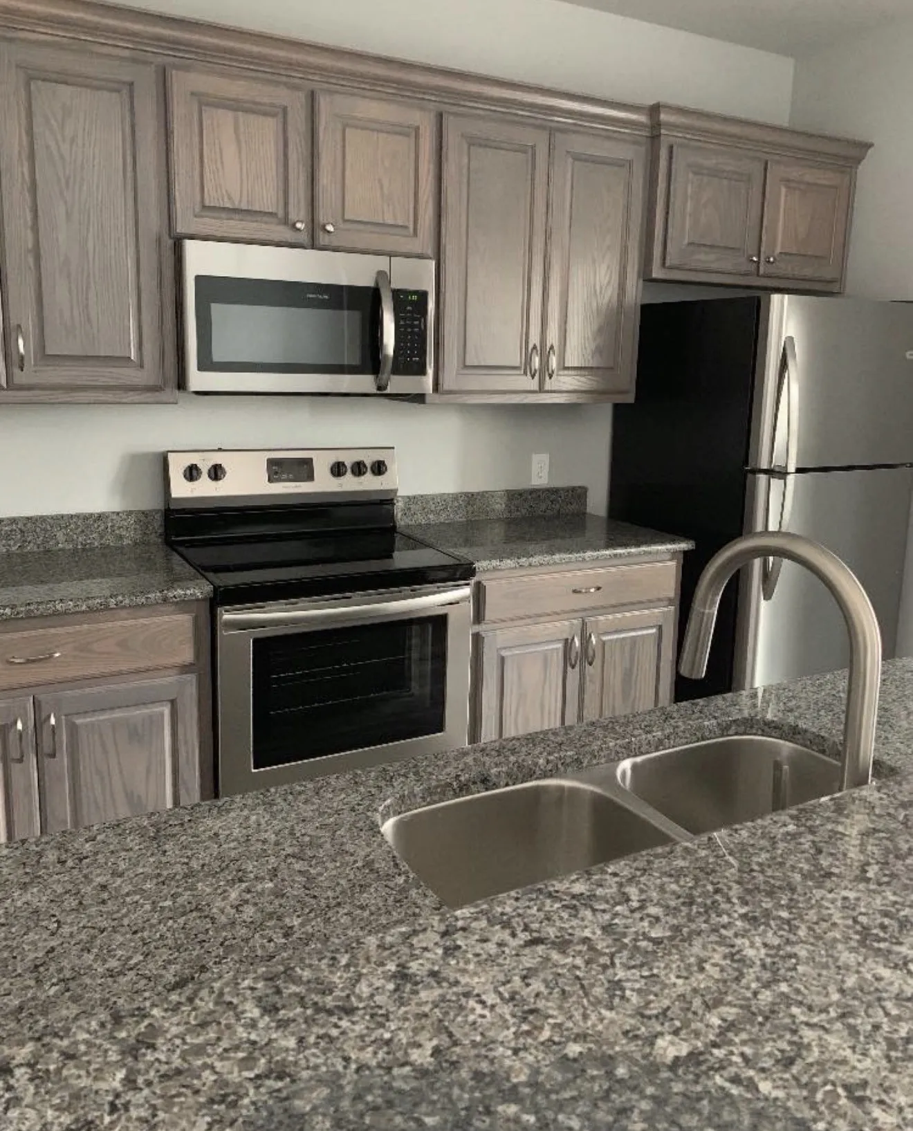 Kitchen featuring gray wood-finish cabinetry, speckled countertops, and stainless steel appliances