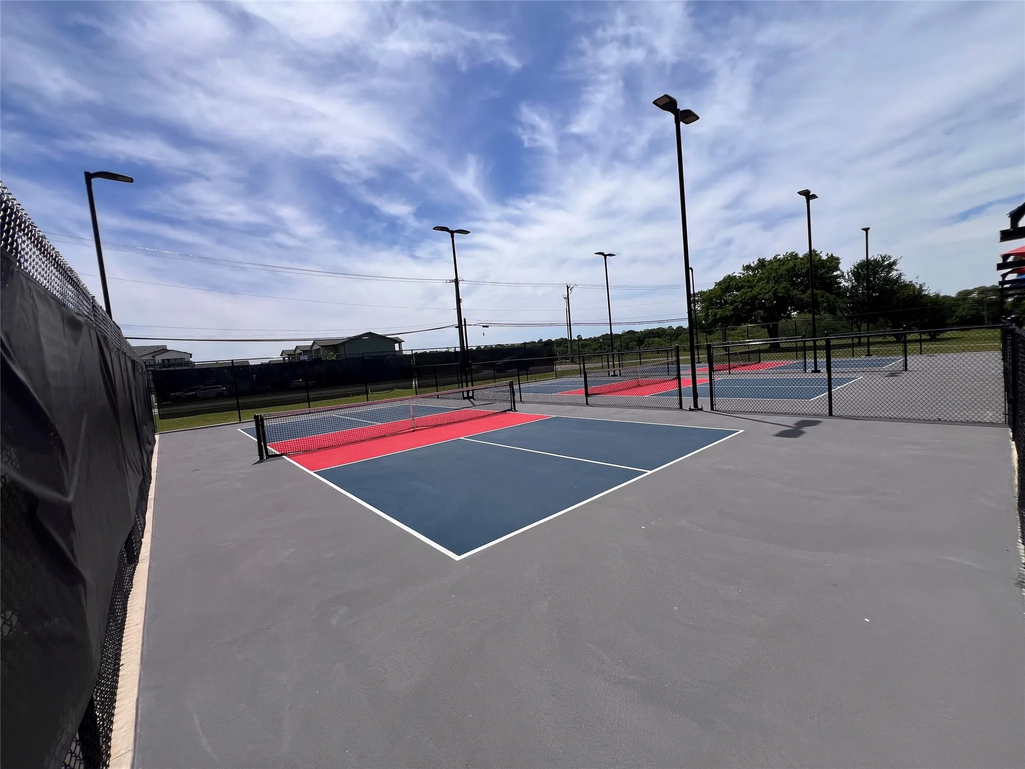 Multiple outdoor courts featuring blue and red playing surfaces with white boundary lines