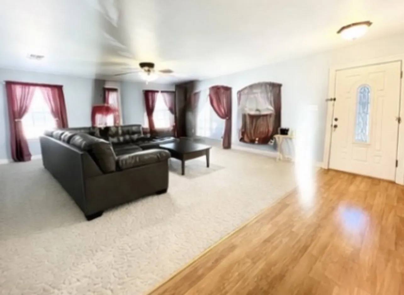 Entryway with wood-finish flooring opening to a carpeted living space