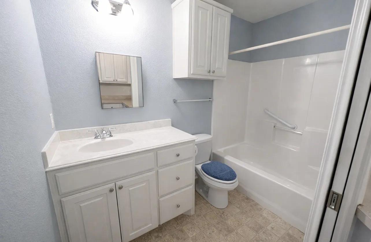 Bathroom featuring a white vanity with an integrated sink, polished chrome faucet, and white cabinet storage