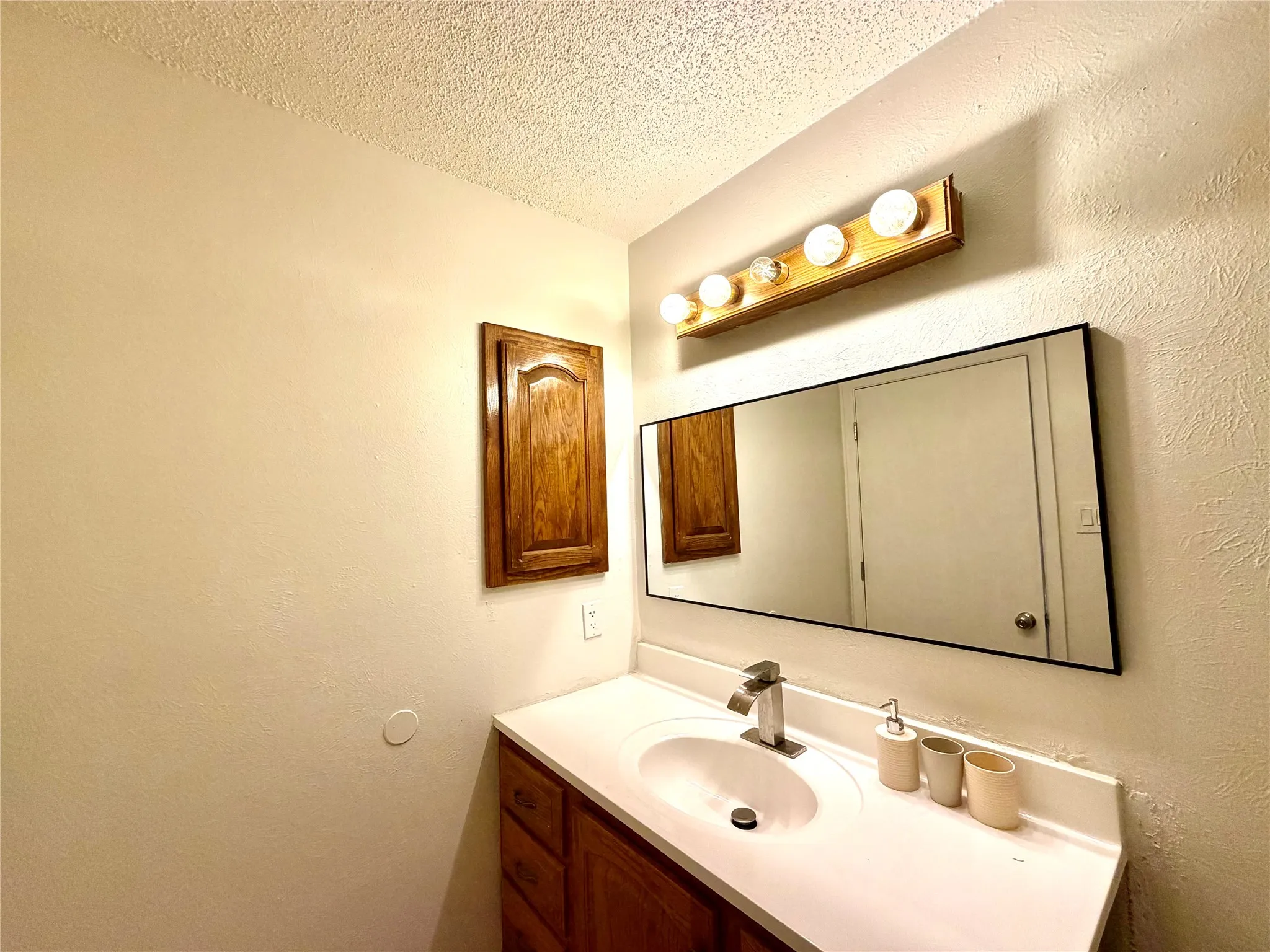 Bathroom vanity featuring a single basin sink, chrome faucet, and white countertop