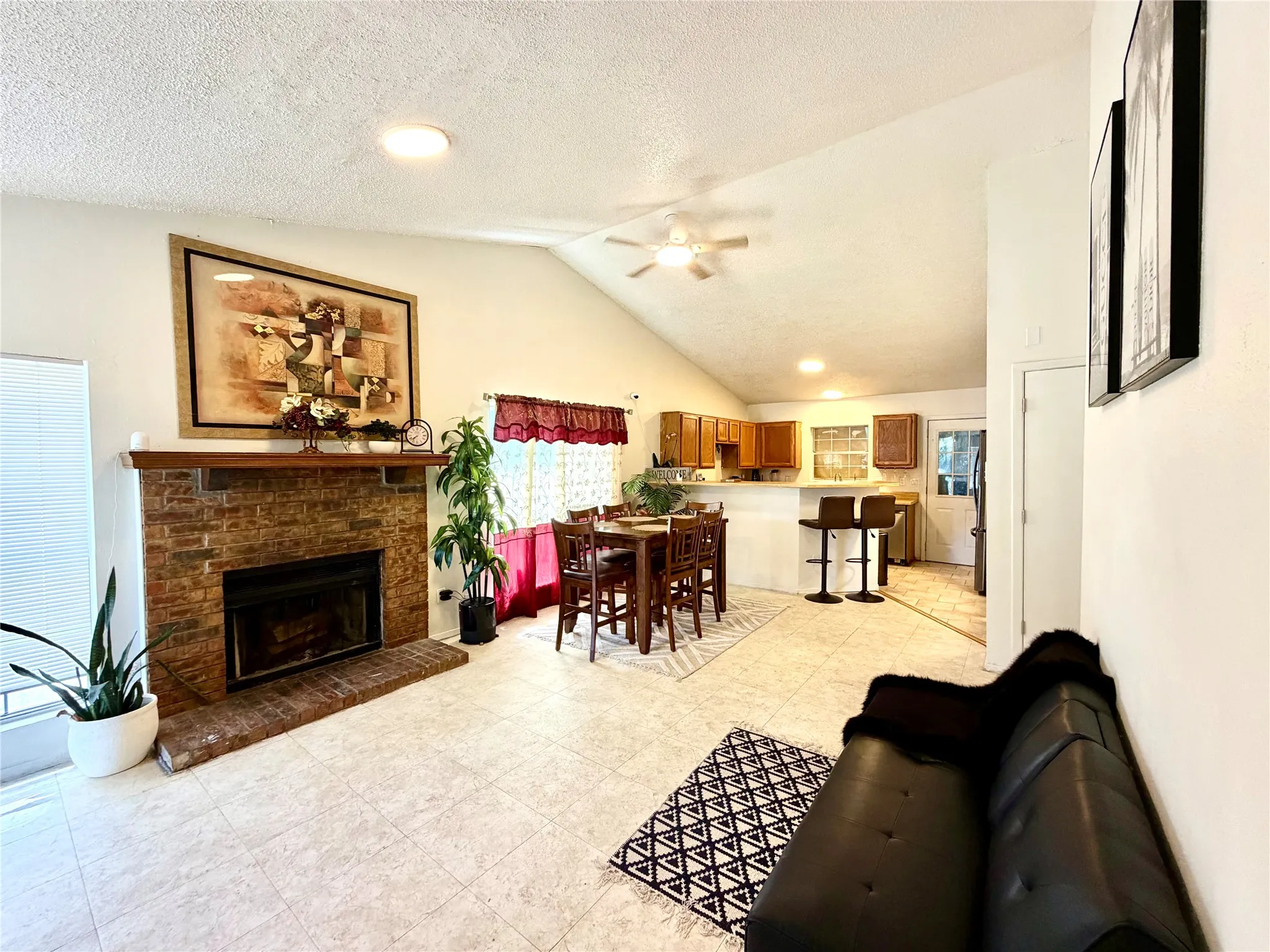 Living area featuring a brick fireplace with a wood mantle, vaulted ceilings, and recessed lighting