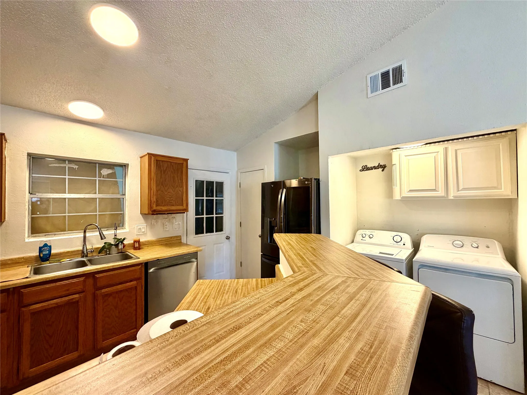 Kitchen area featuring a wood-finish countertop bar, stainless steel sink, wood cabinetry, and a full-light rear door