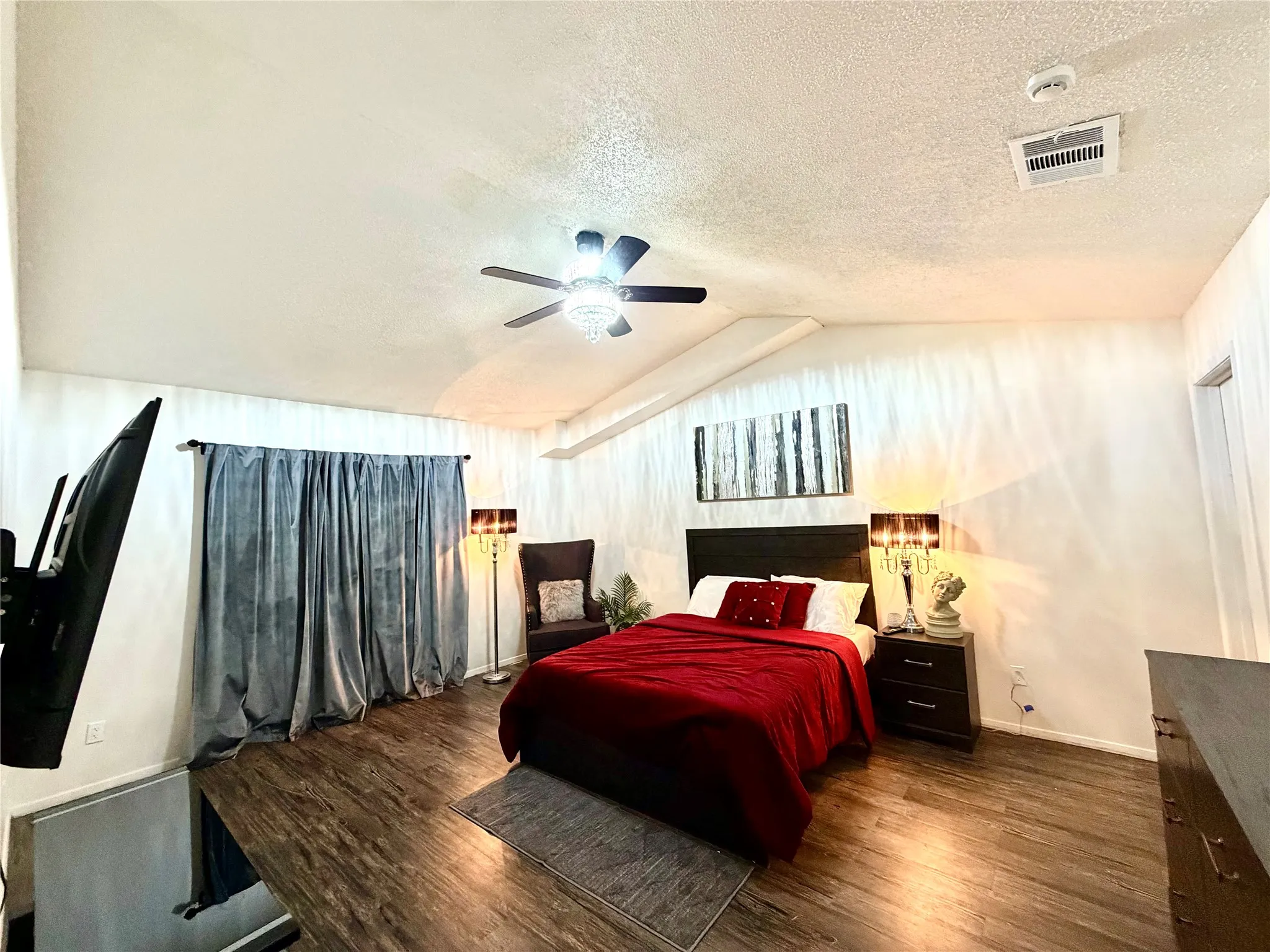 Spacious room featuring vaulted ceilings, wood-finish flooring, and a ceiling fan with integrated lighting