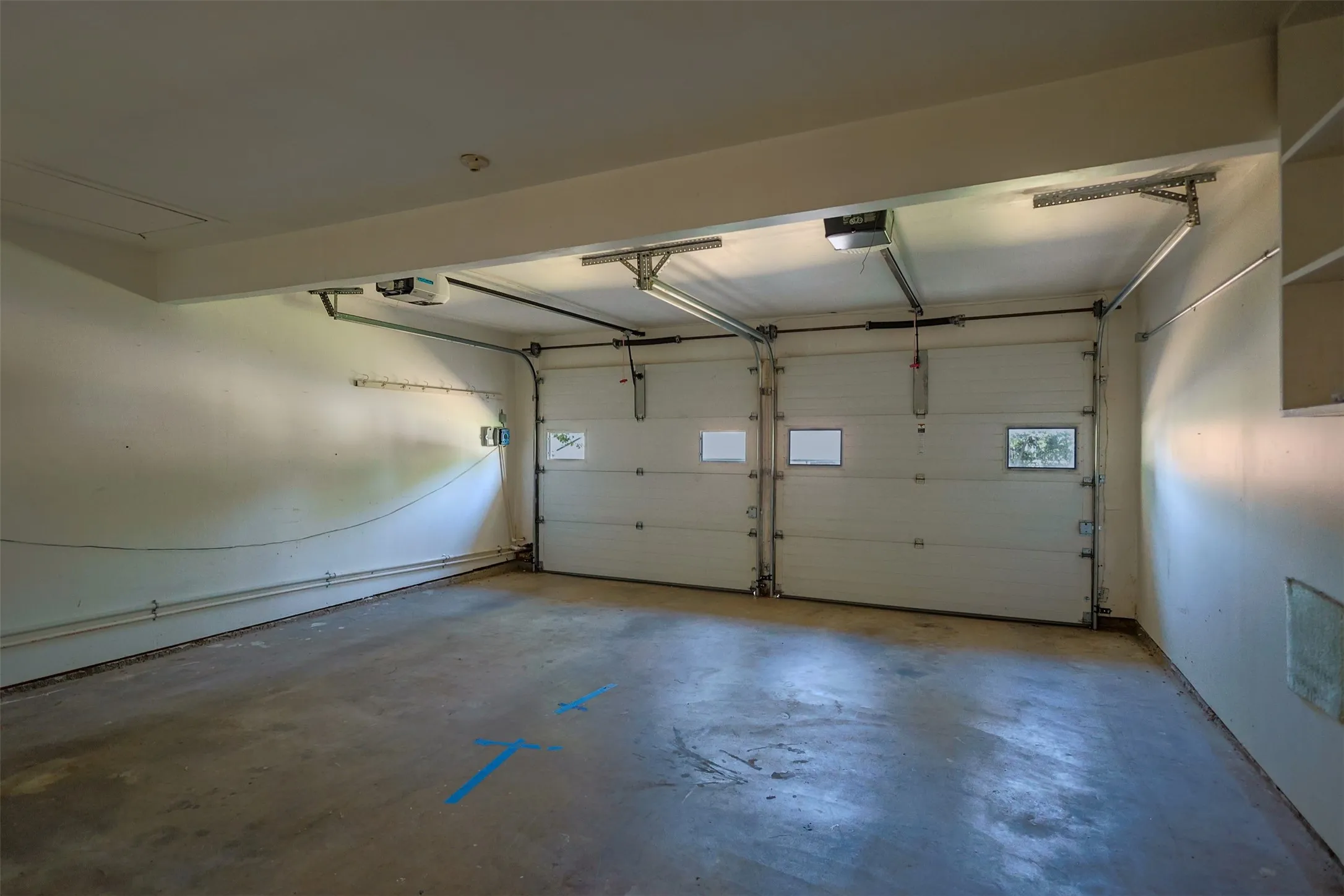 Two-car garage featuring a concrete floor, two garage doors with upper window inserts, and built-in shelving