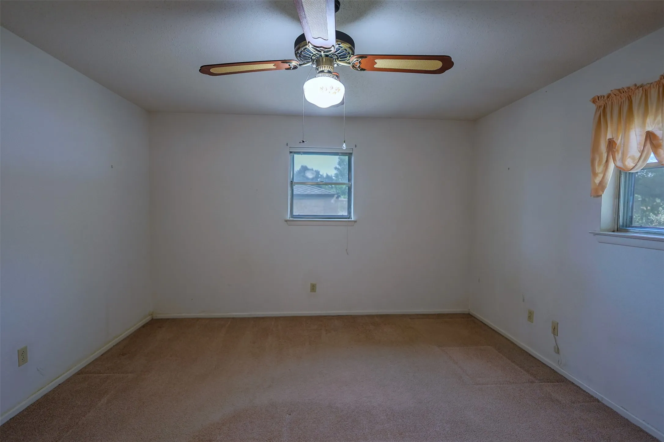 Carpeted room featuring a ceiling fan with integrated lighting, two windows with window sills, and white painted walls