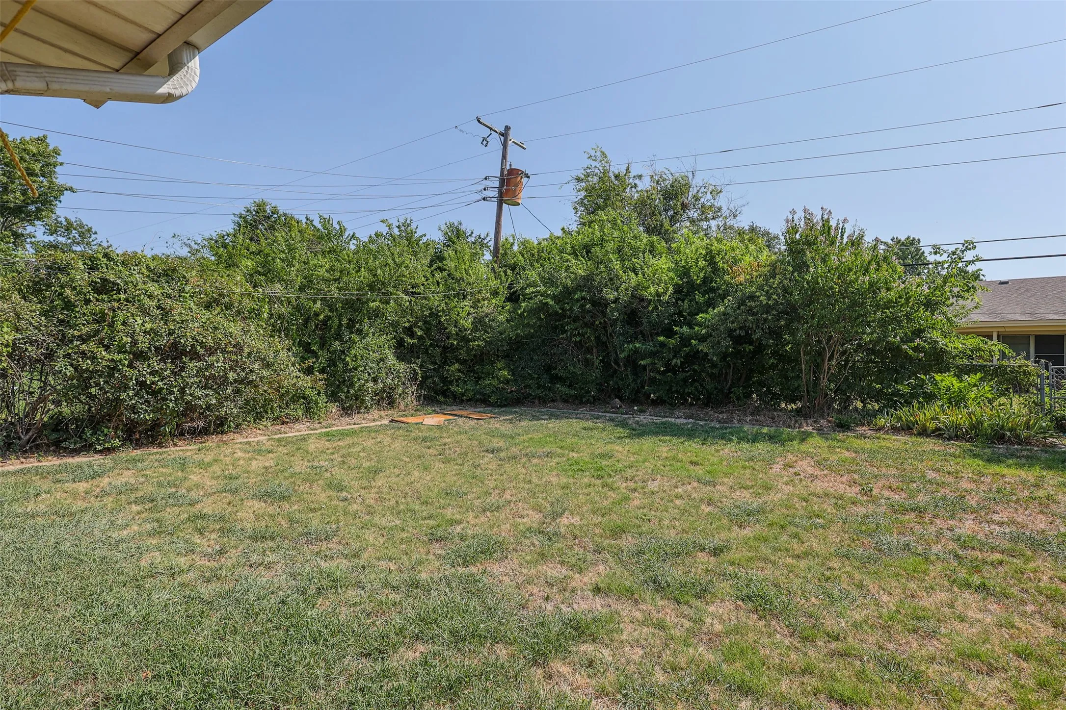 Expansive backyard featuring a grass lawn and mature perimeter landscaping